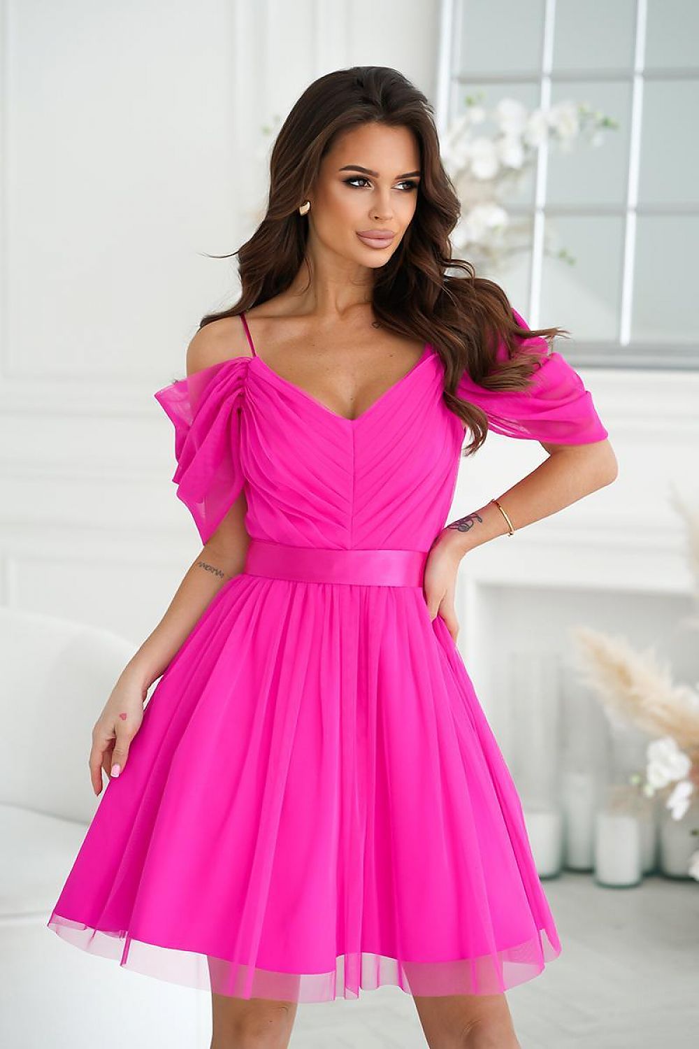 Woman wearing a bright pink dress with a white background