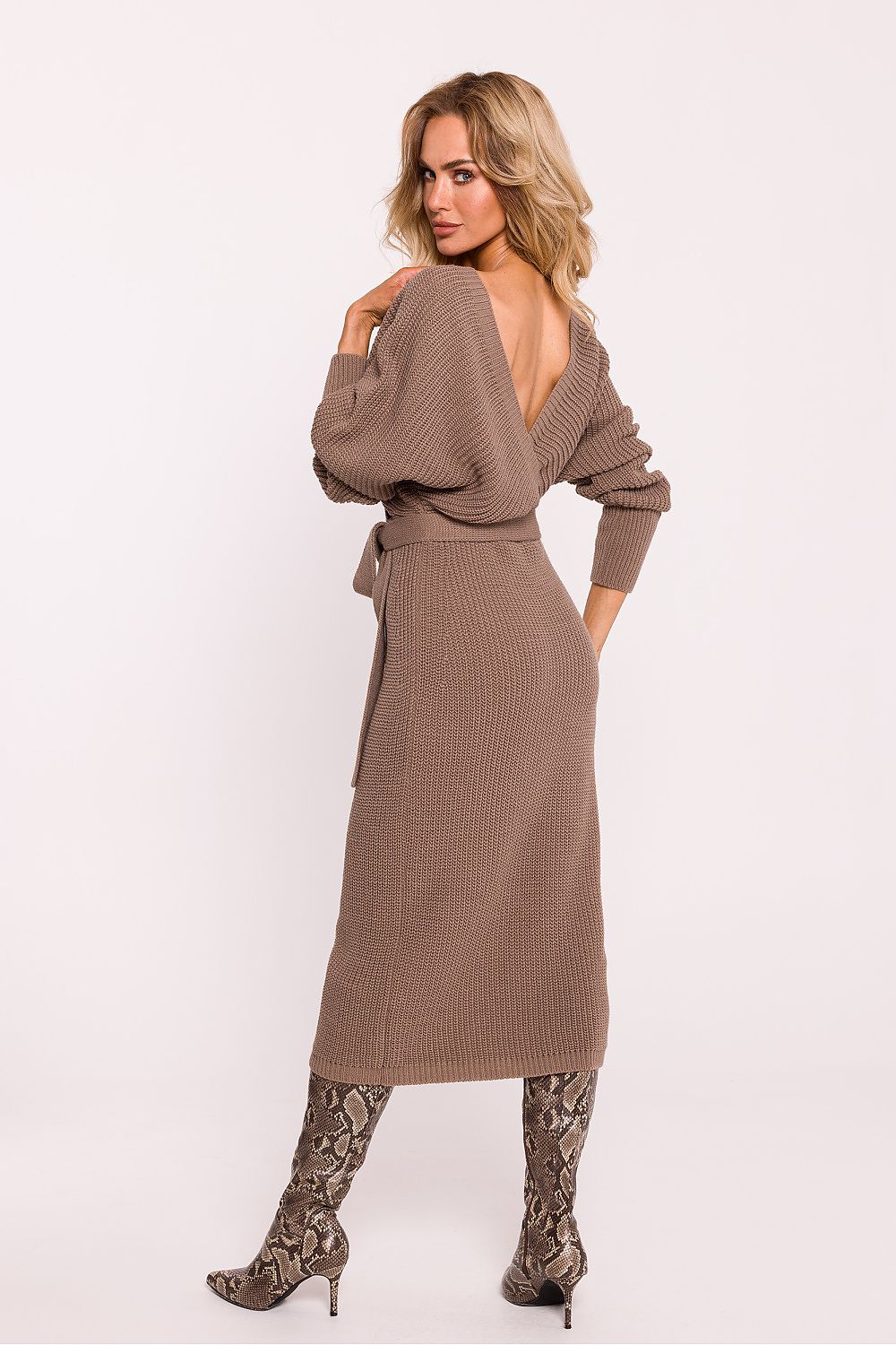 Woman wearing a brown ribbed dress with a belt on a white background
