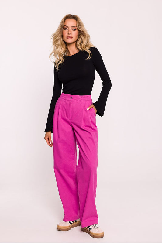 Woman wearing a black top and pink pants on a white background