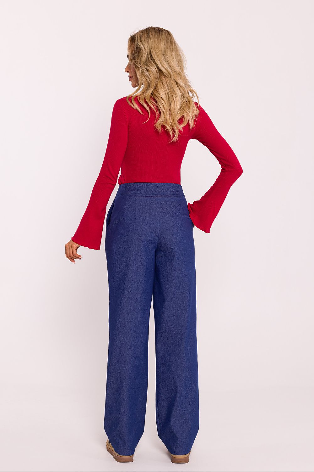 Woman wearing a red top and blue pants on a white background