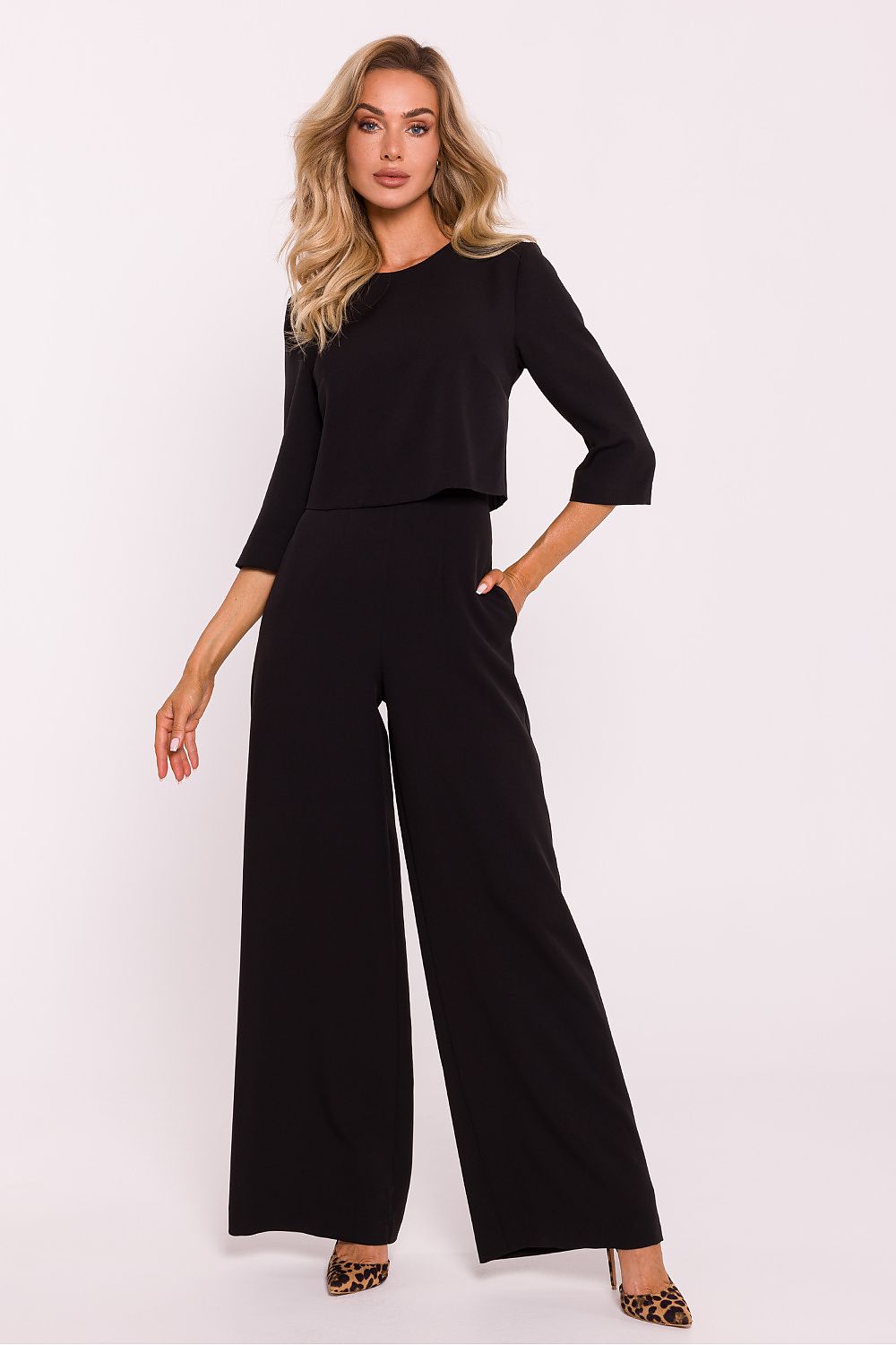 Woman wearing a black outfit with wide-leg pants on a white background