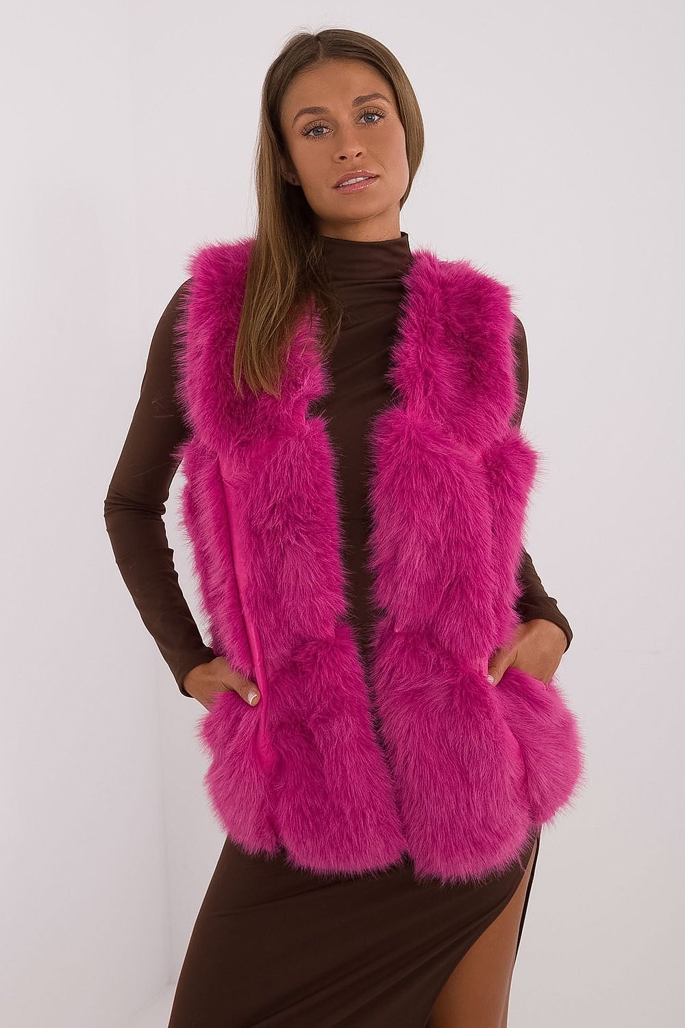 Woman wearing a bright pink fur vest against a white background