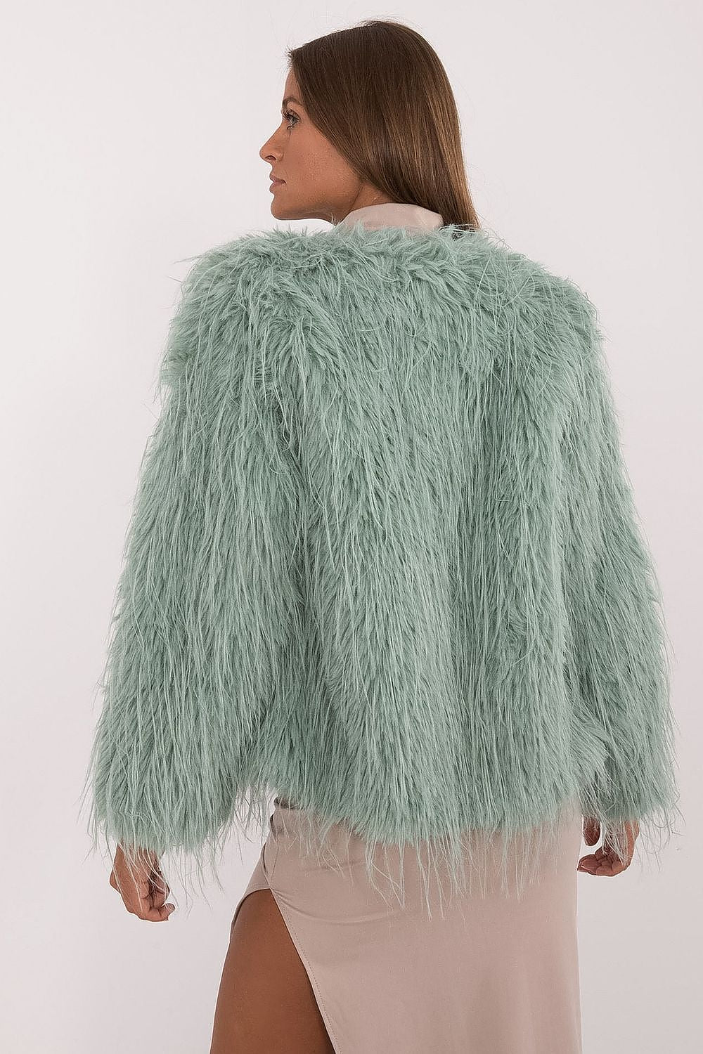 Person wearing a light green fluffy jacket on a white background