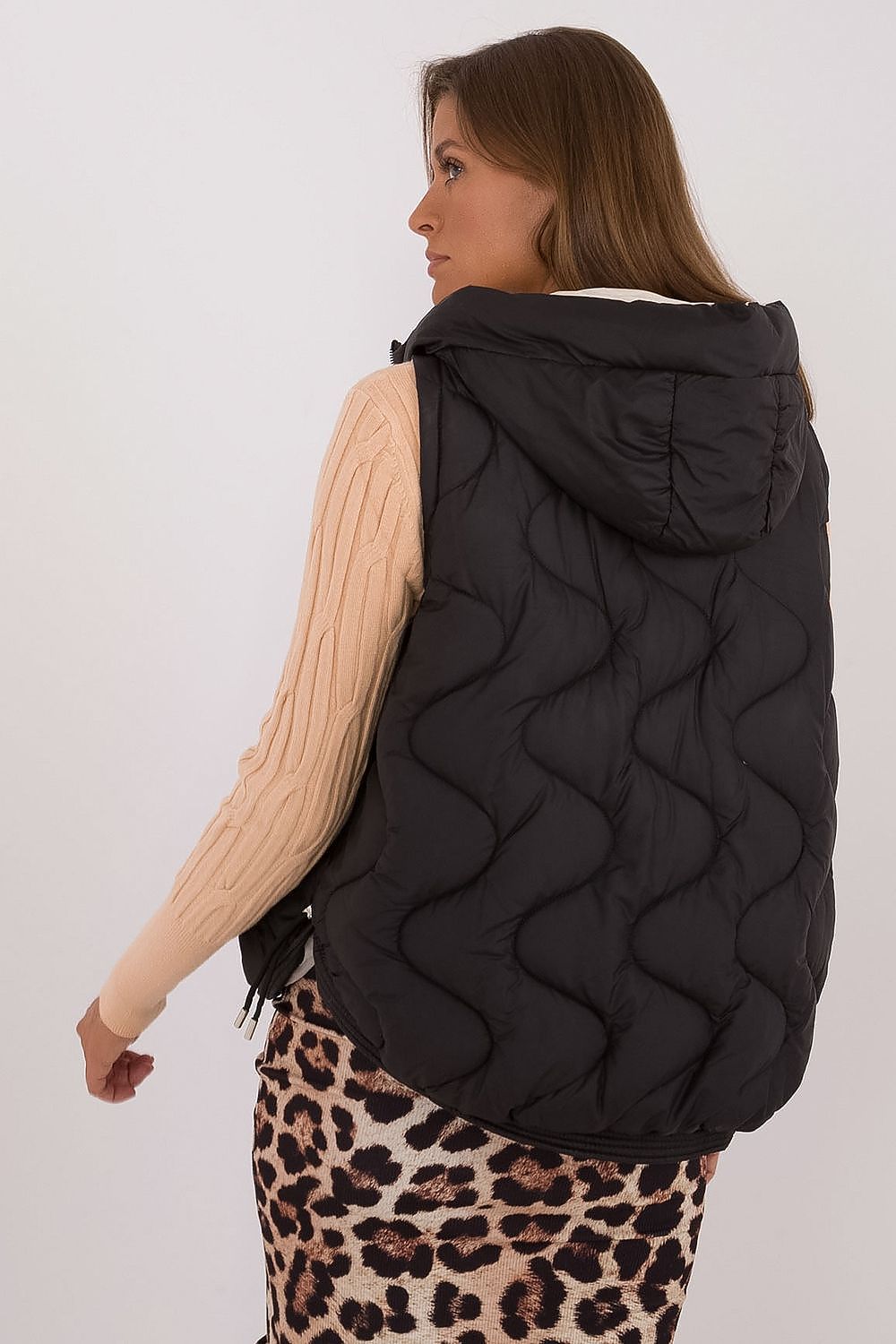 Woman wearing a black quilted vest with a neutral background