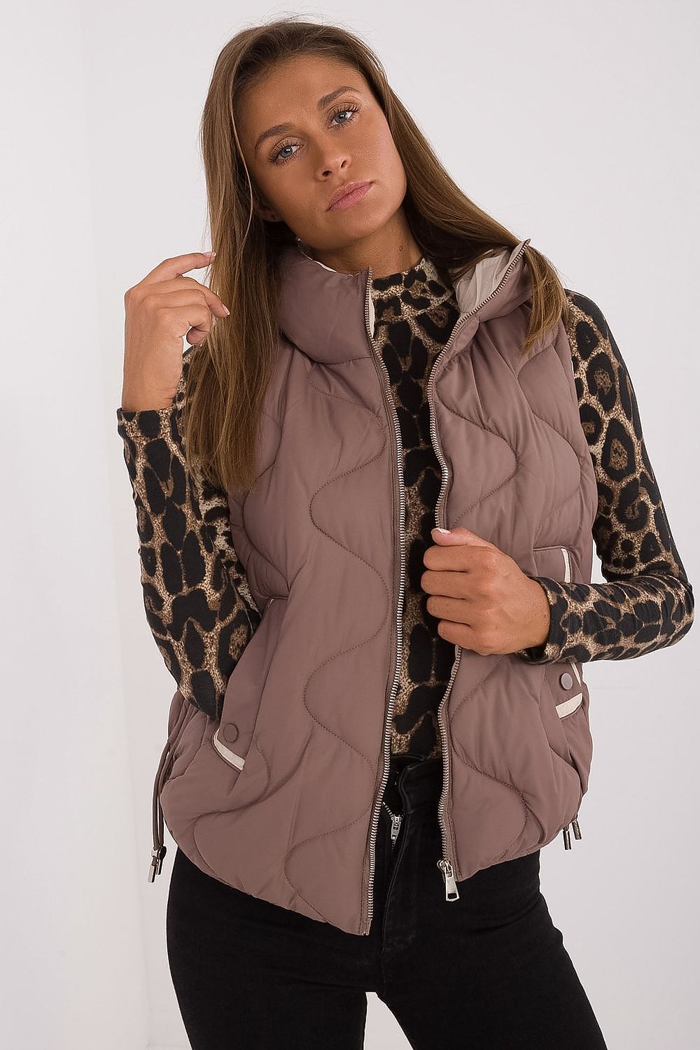 Woman wearing a quilted vest over a leopard print shirt on a white background