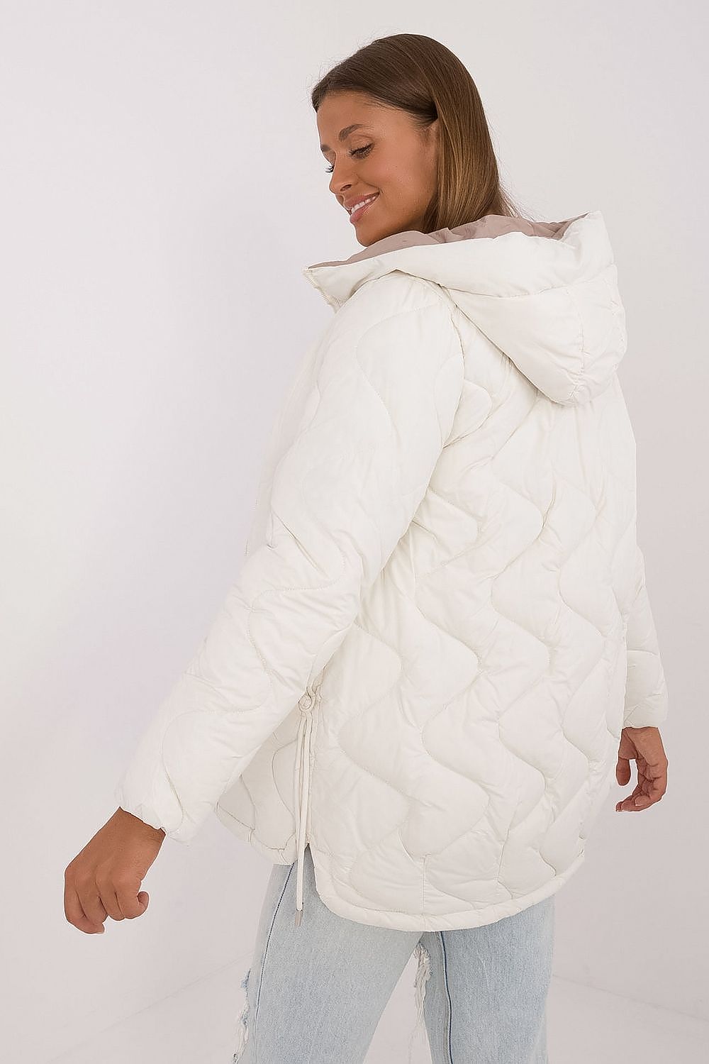 Woman wearing a white puffer jacket on a plain background
