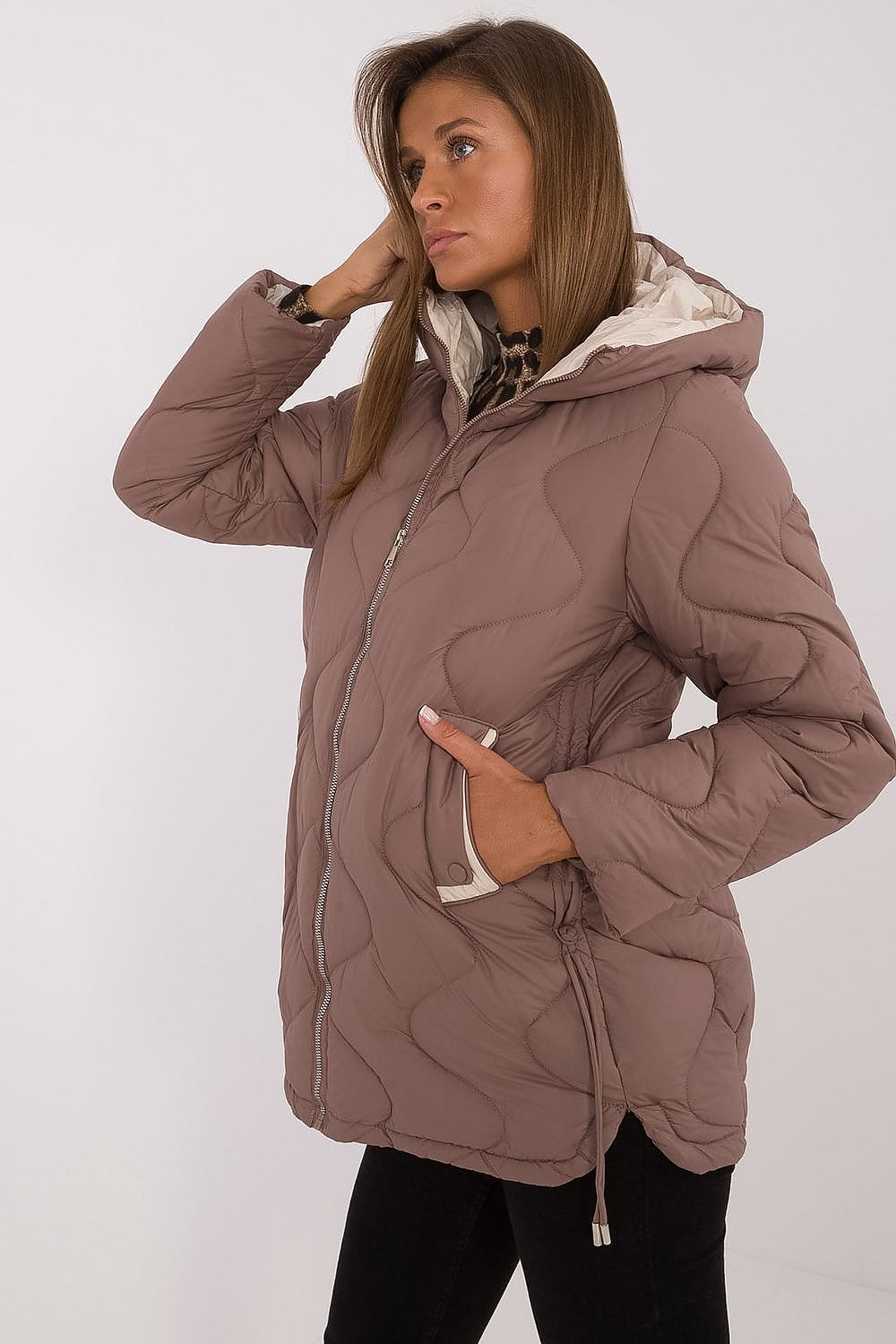 Woman wearing a brown quilted jacket with a white background