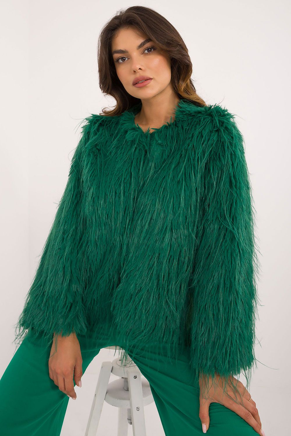 Woman wearing a green fluffy jacket on a white background