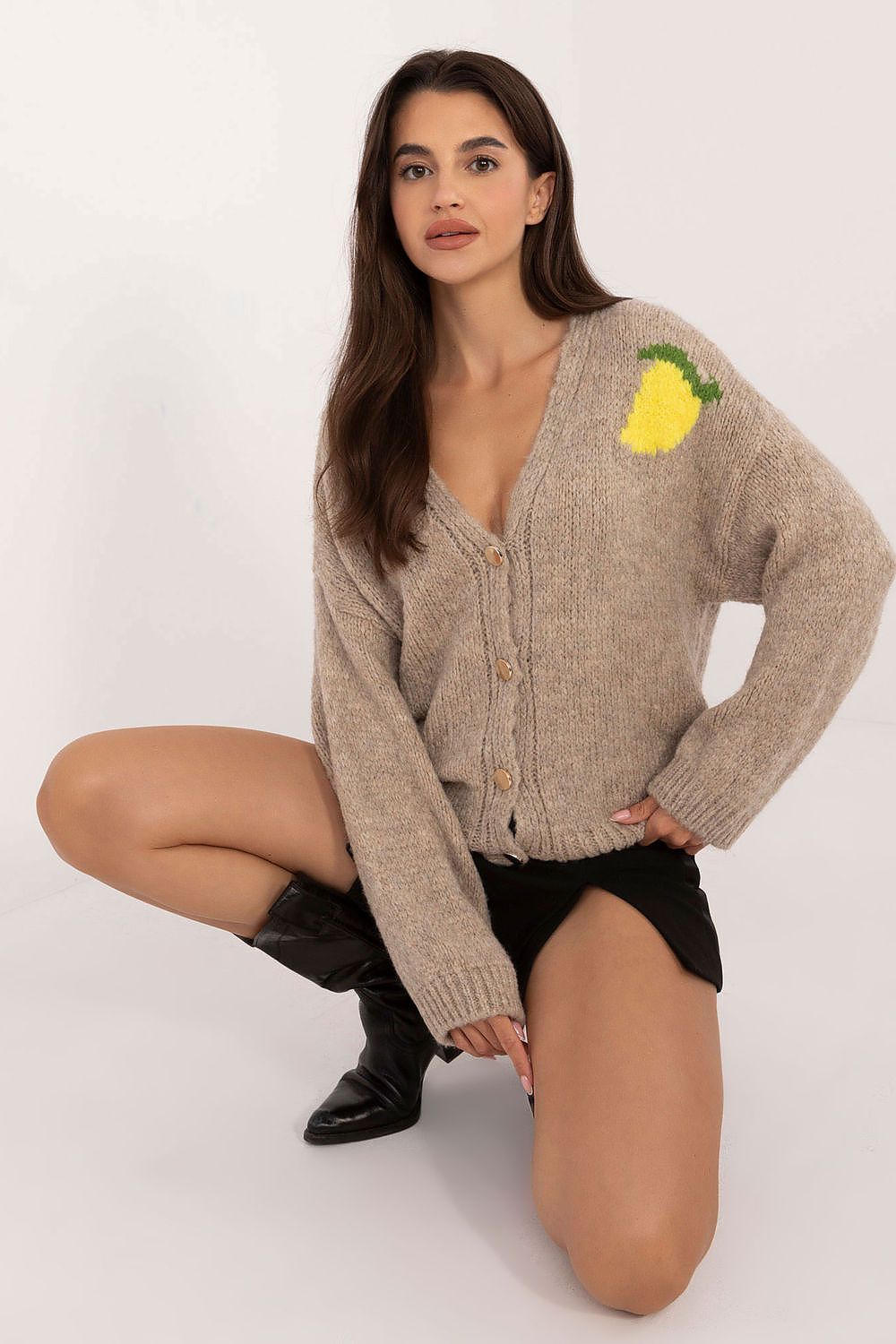 Woman wearing a beige cardigan with a lemon design on a white background
