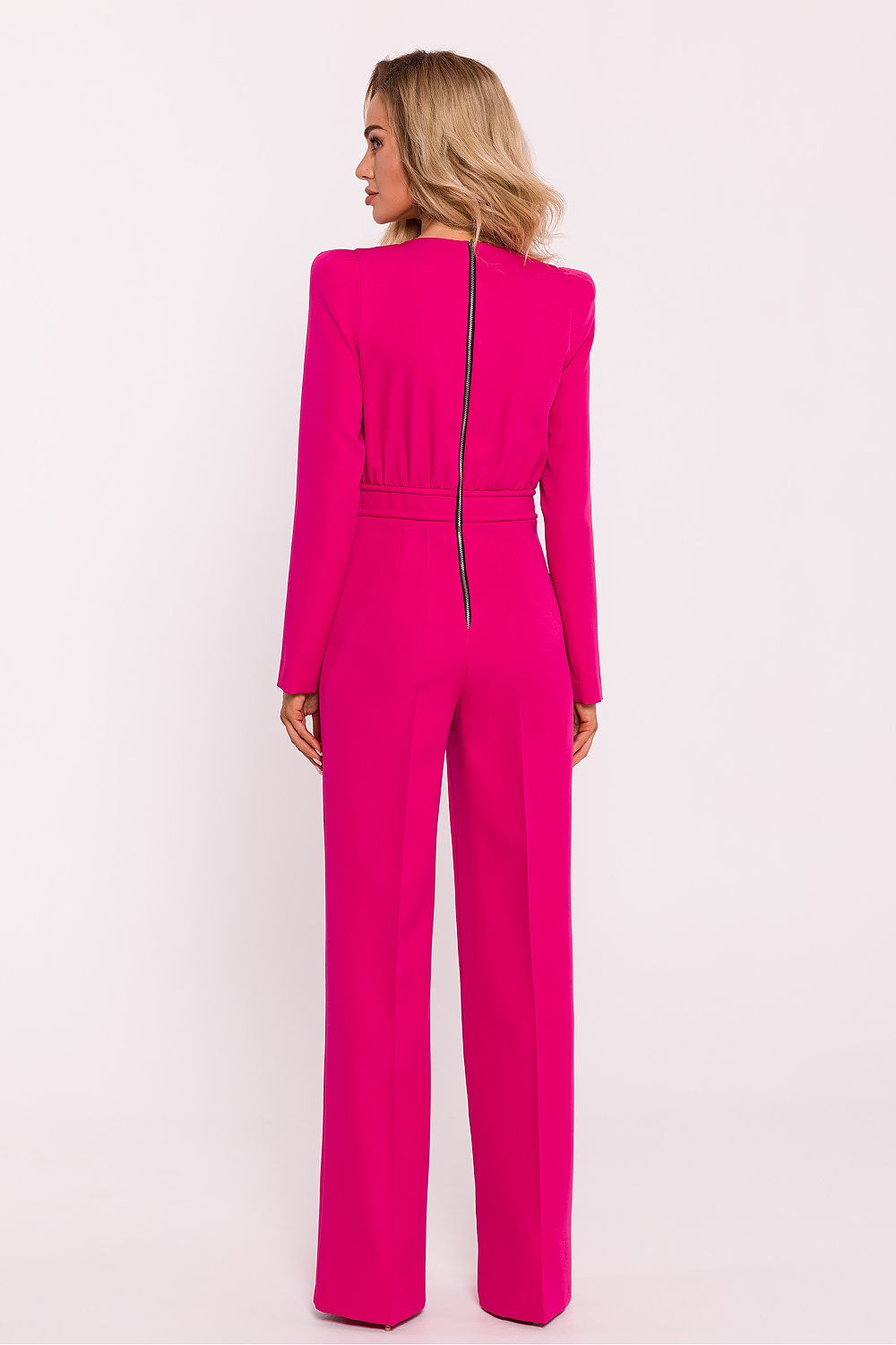 Woman wearing a bright pink jumpsuit on a white background