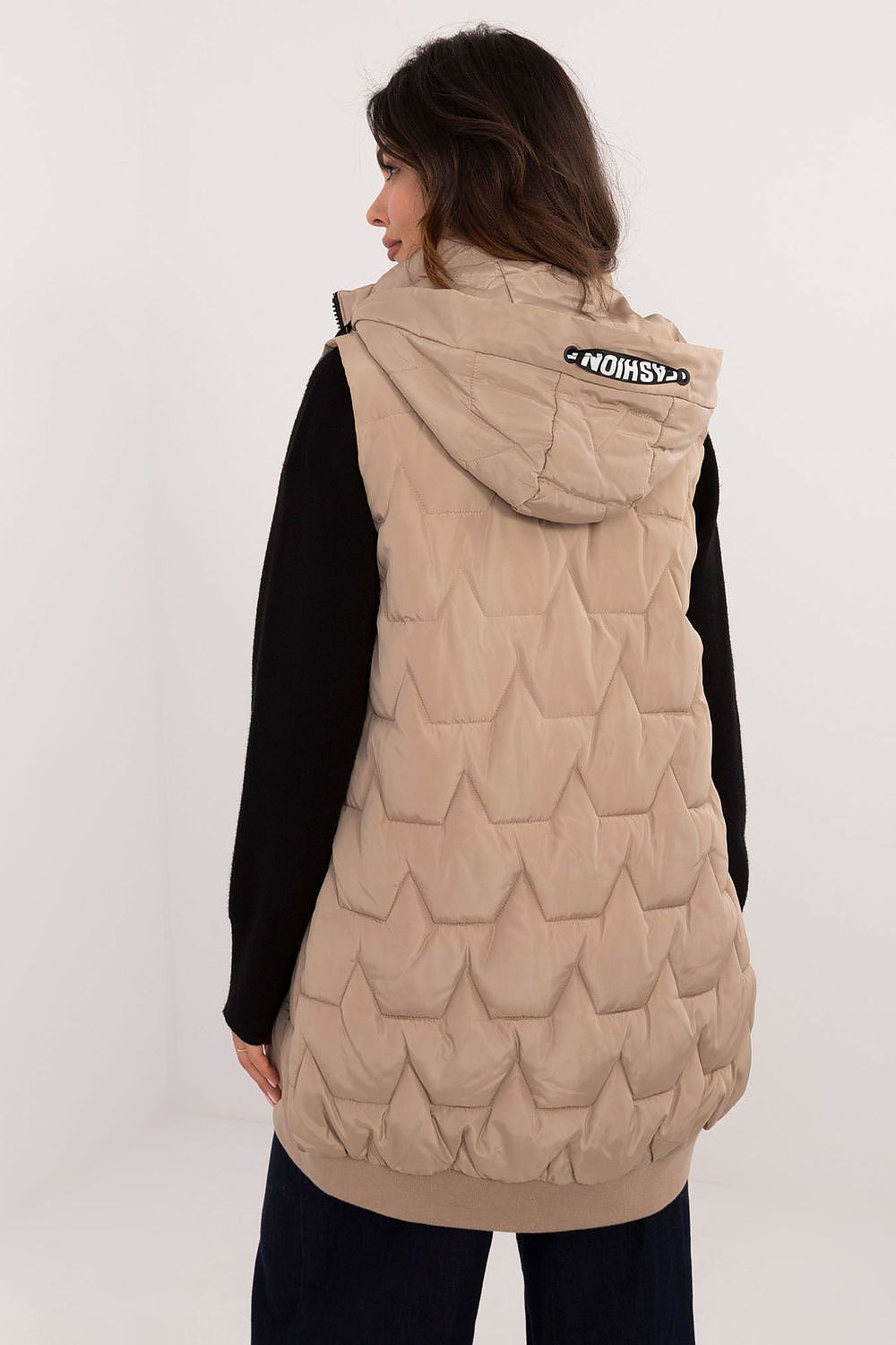 Person wearing a beige quilted vest with a brand logo on a white background