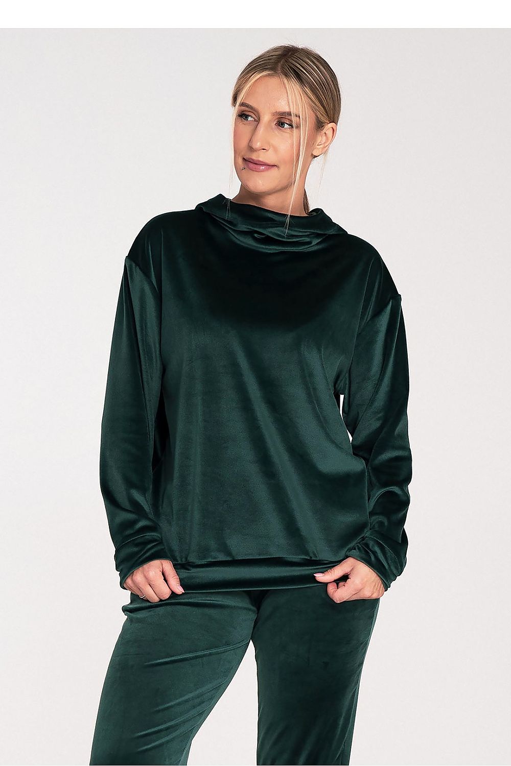 Woman wearing a dark green long-sleeve top and pants on a white background