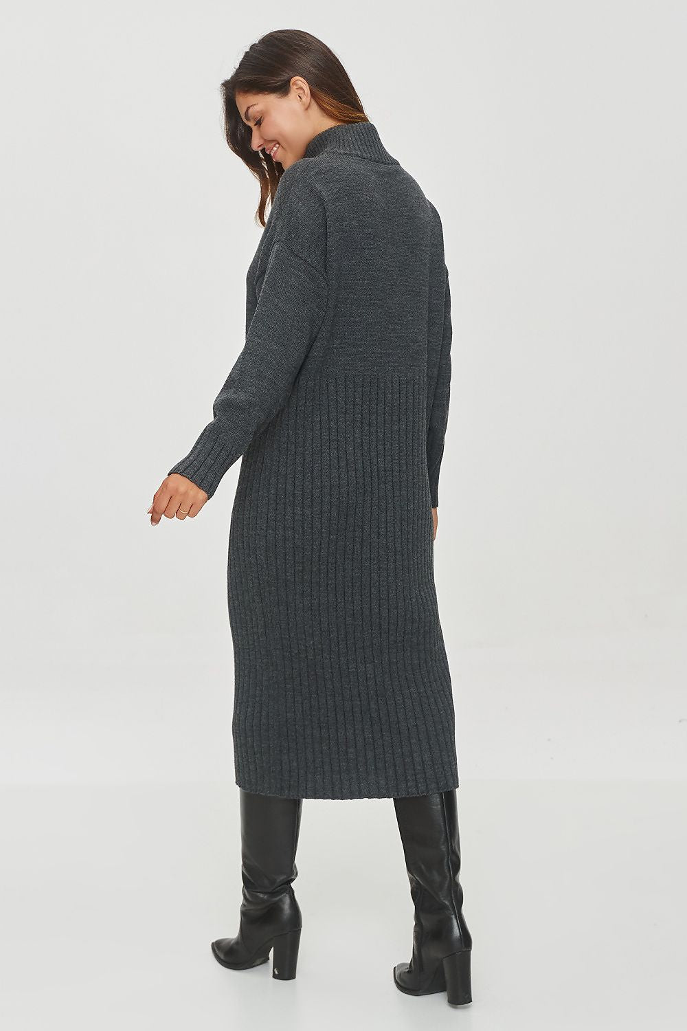 Woman wearing a long dark gray ribbed sweater dress on a white background