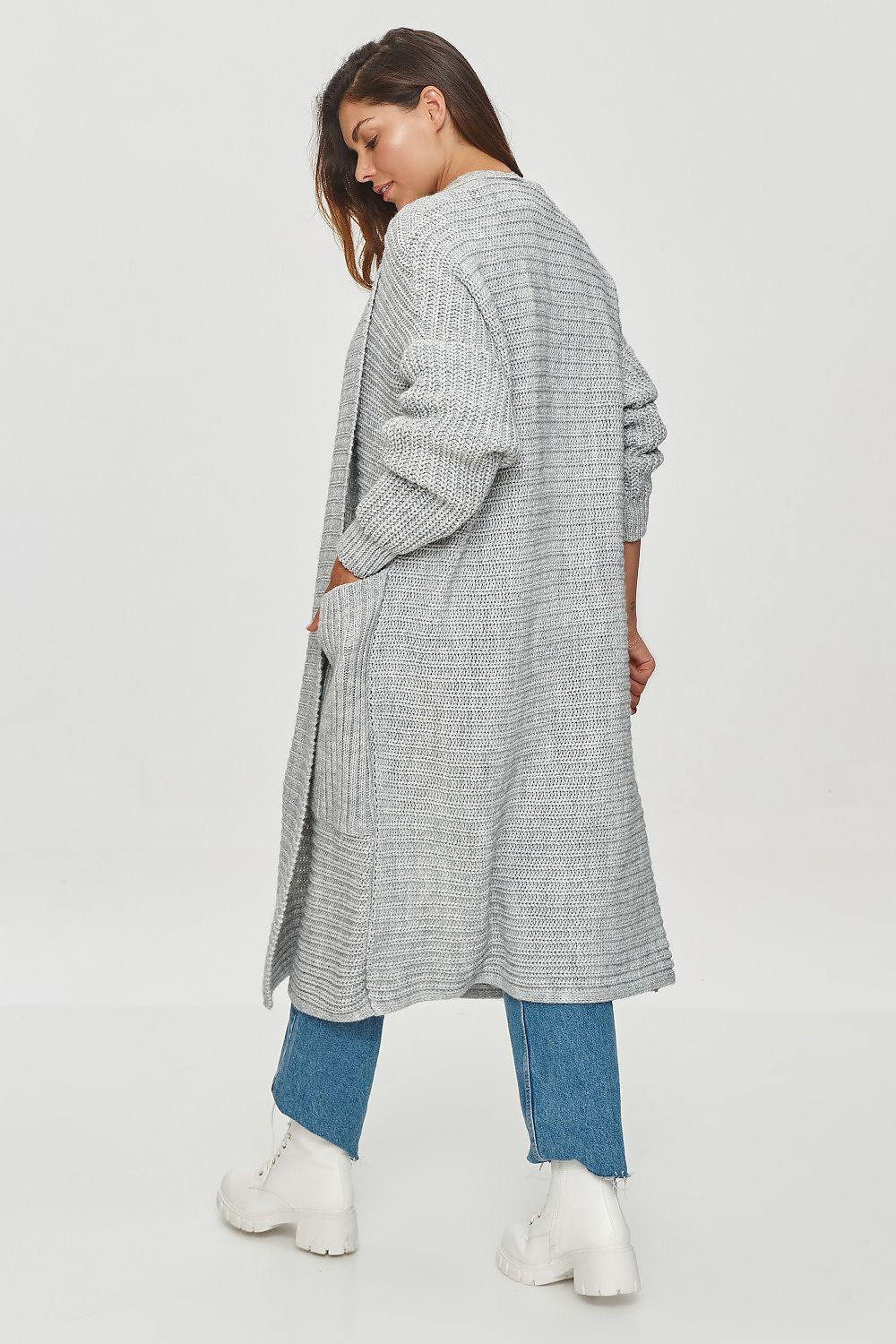 Woman wearing a long, light gray checkered cardigan over a blue outfit on a white background