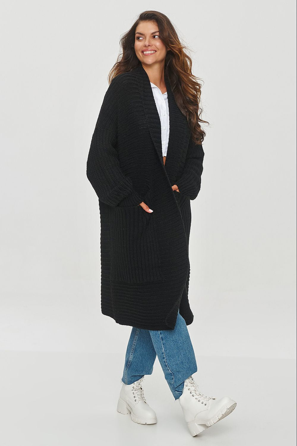 Woman wearing a black long coat on a light gray background