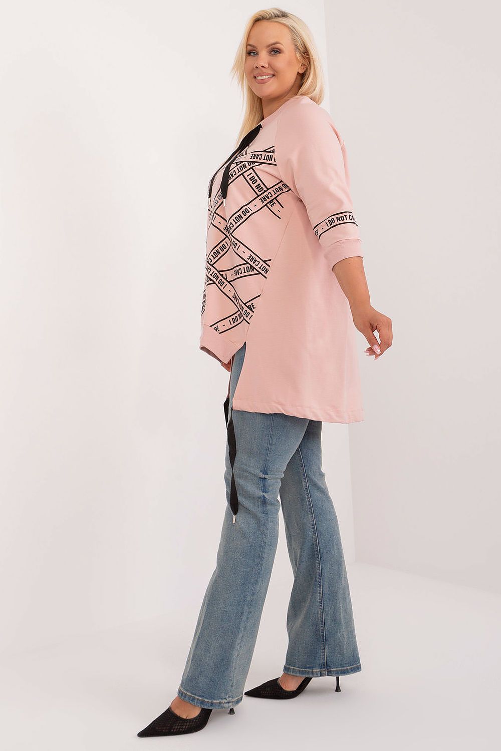 Woman wearing a pink jacket with black patterns and blue jeans on a white background