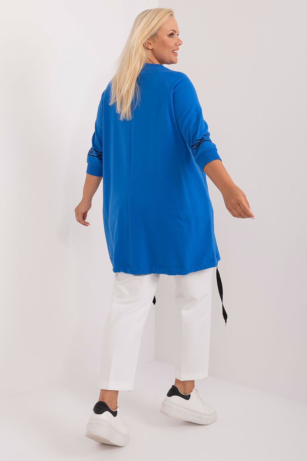 Woman wearing a blue top and white pants on a white background