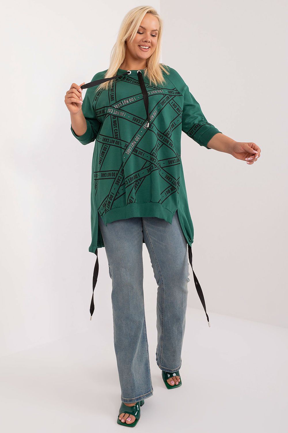 Woman wearing a green patterned top and blue jeans on a white background