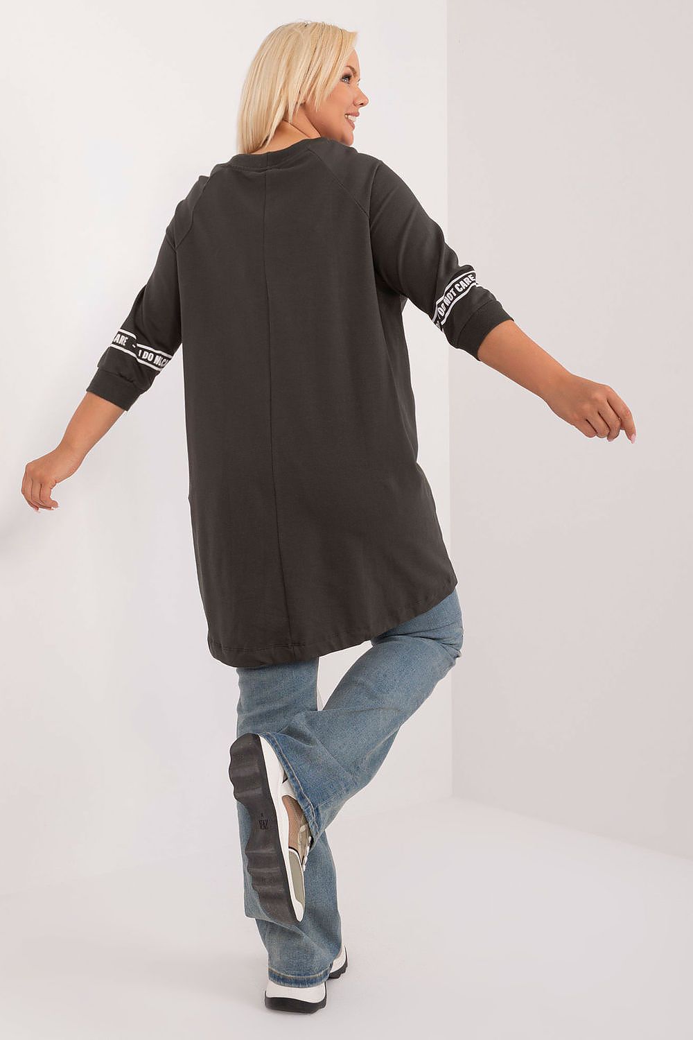 Woman wearing a black long-sleeve top with white text on sleeves, standing against a white background.