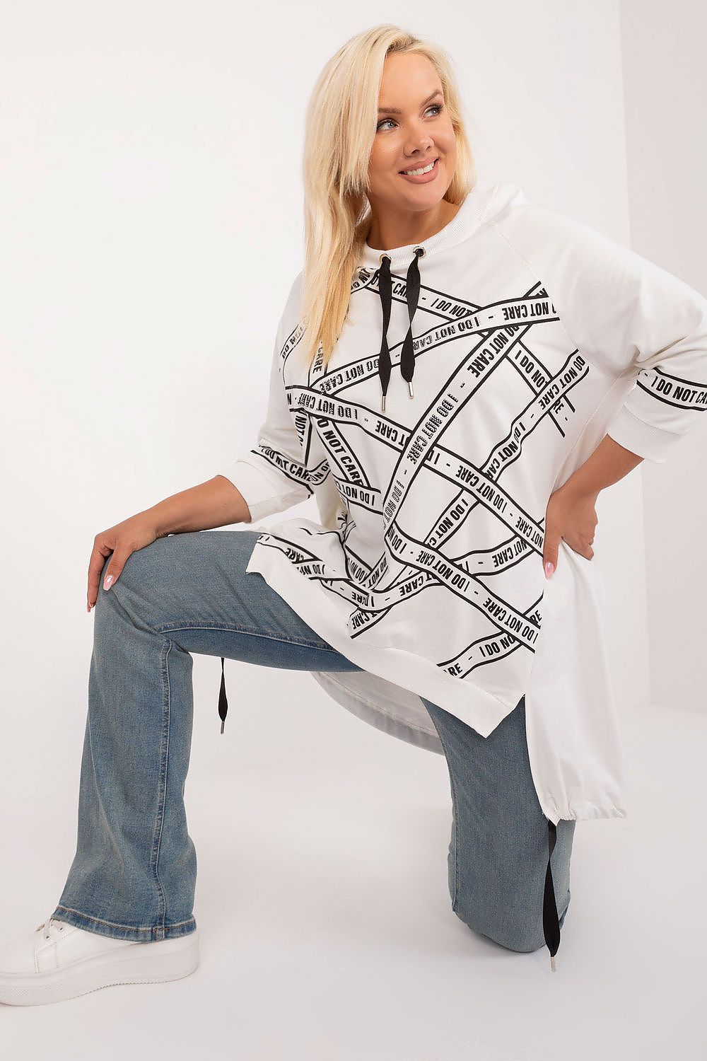 Woman wearing a white poncho with black text design over a white background