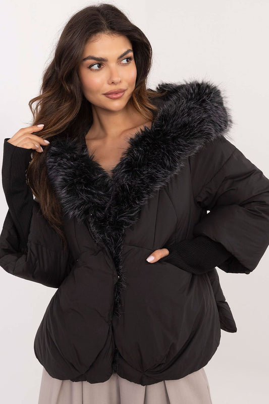 Woman wearing a black puffer jacket with fur trim on a white background