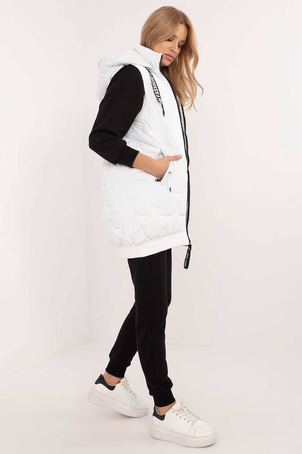Woman wearing a white puffer vest over a black outfit on a white background