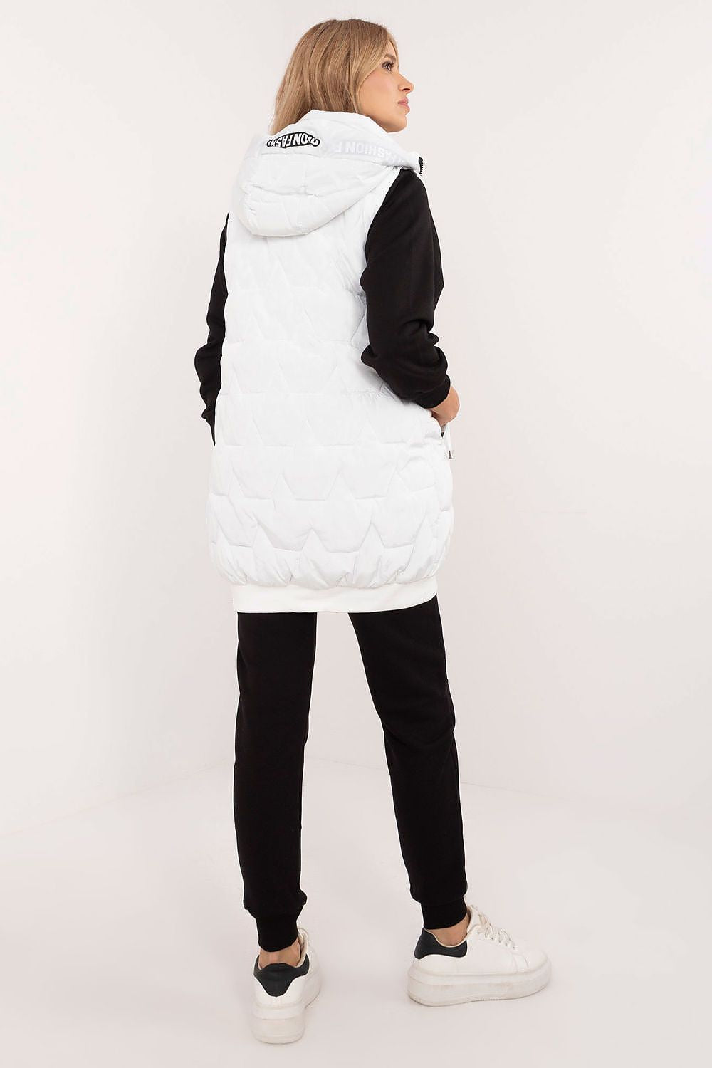 Person wearing a white puffer vest with a brand logo on a white background