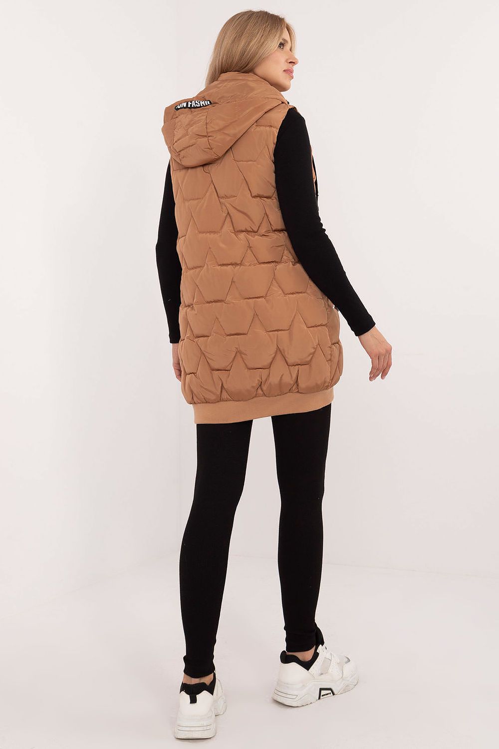 Woman wearing a brown quilted vest on a white background