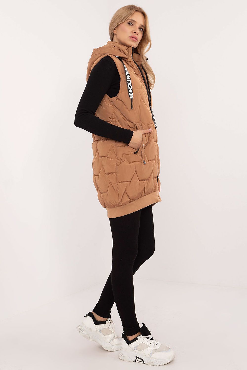 Woman wearing a brown quilted vest over a black top on a white background
