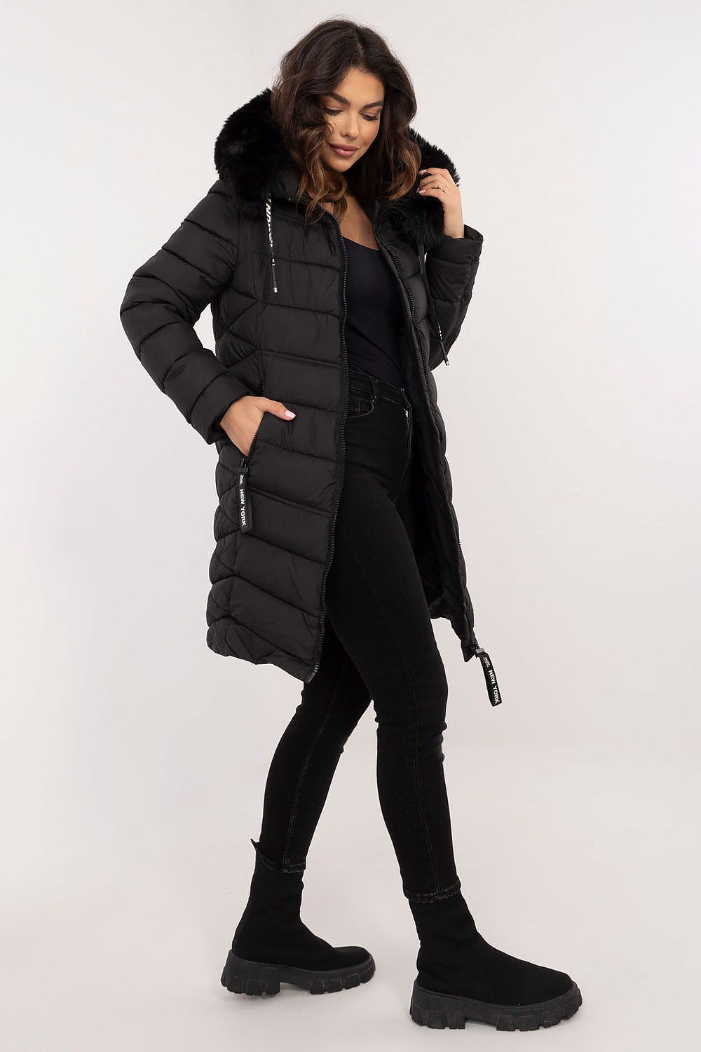 Woman wearing a black puffer coat on a white background