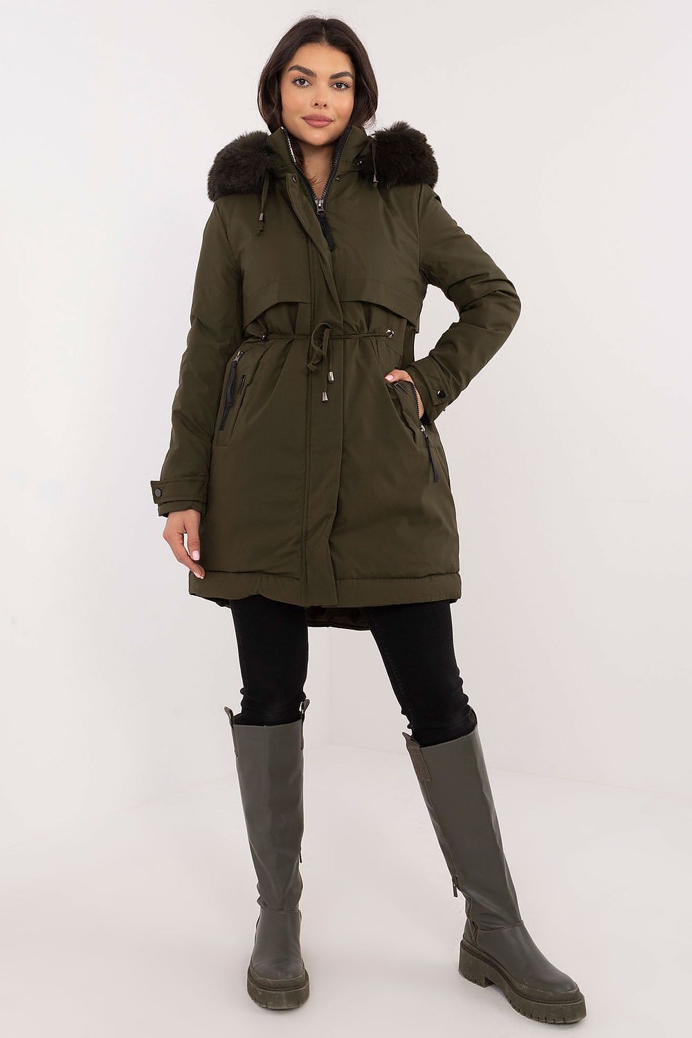 Woman wearing a green parka with fur hood and matching boots on a white background