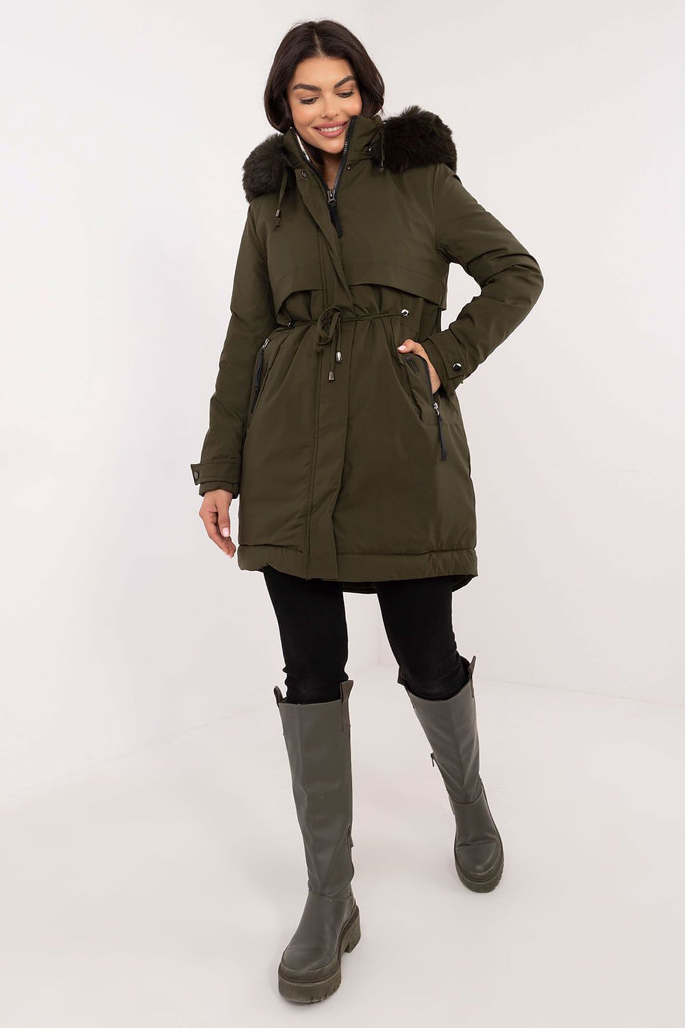 Woman wearing an olive green parka with fur hood on a white background