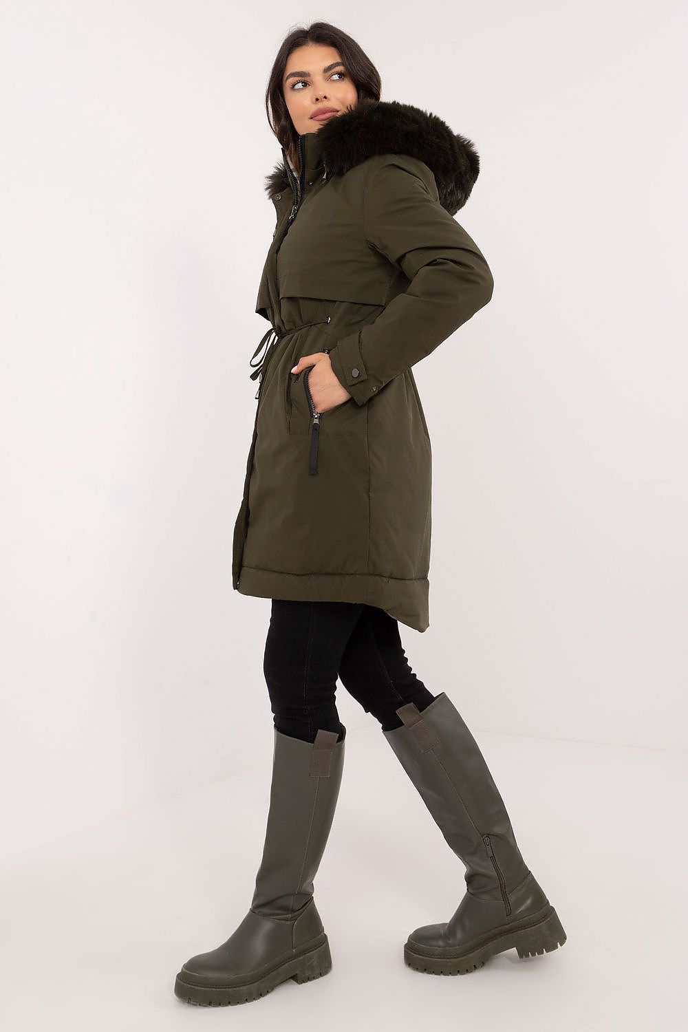 Woman wearing a green parka with a fur-lined hood on a white background