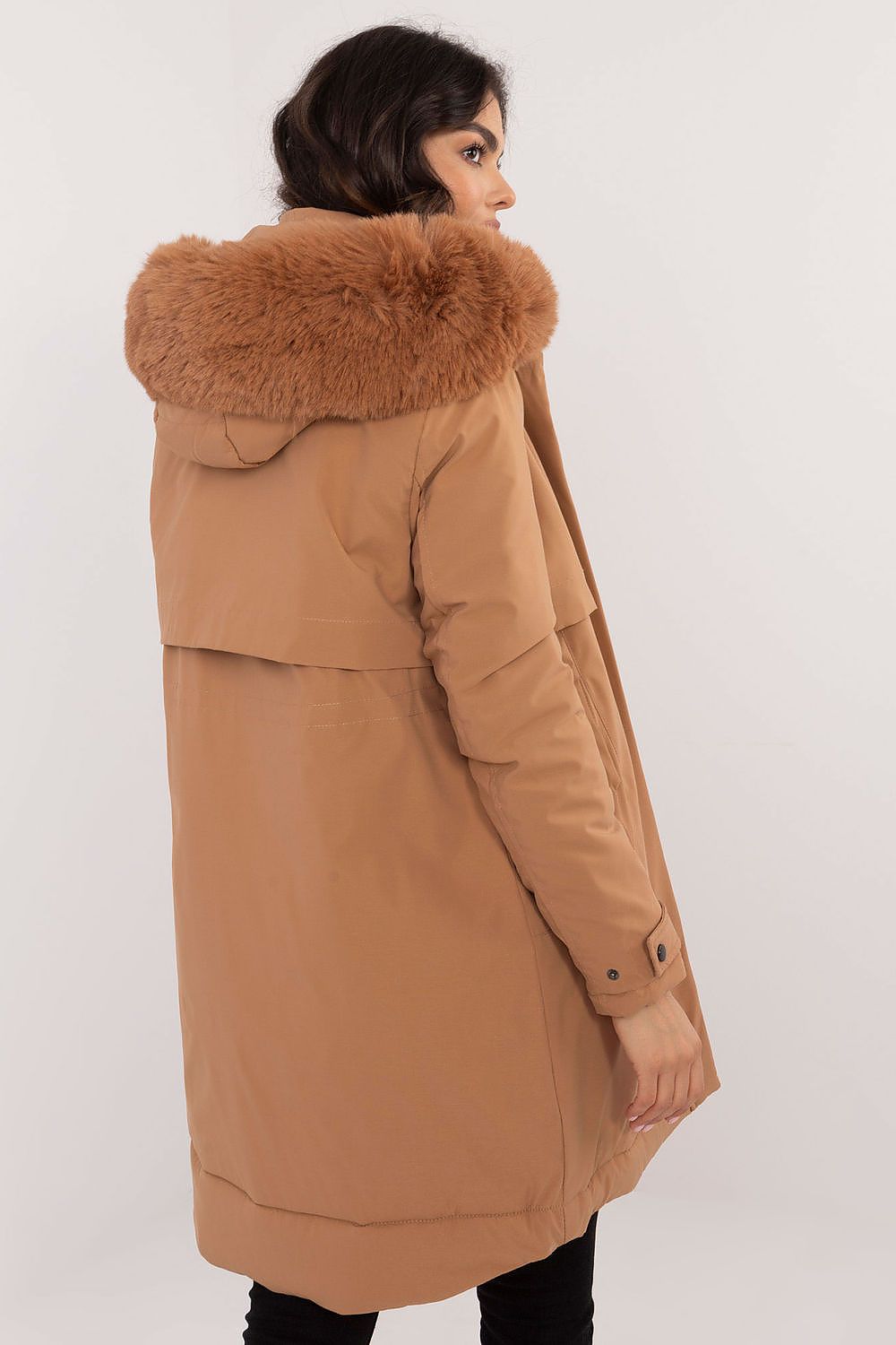 Brown coat with fur hood worn by a person on a white background