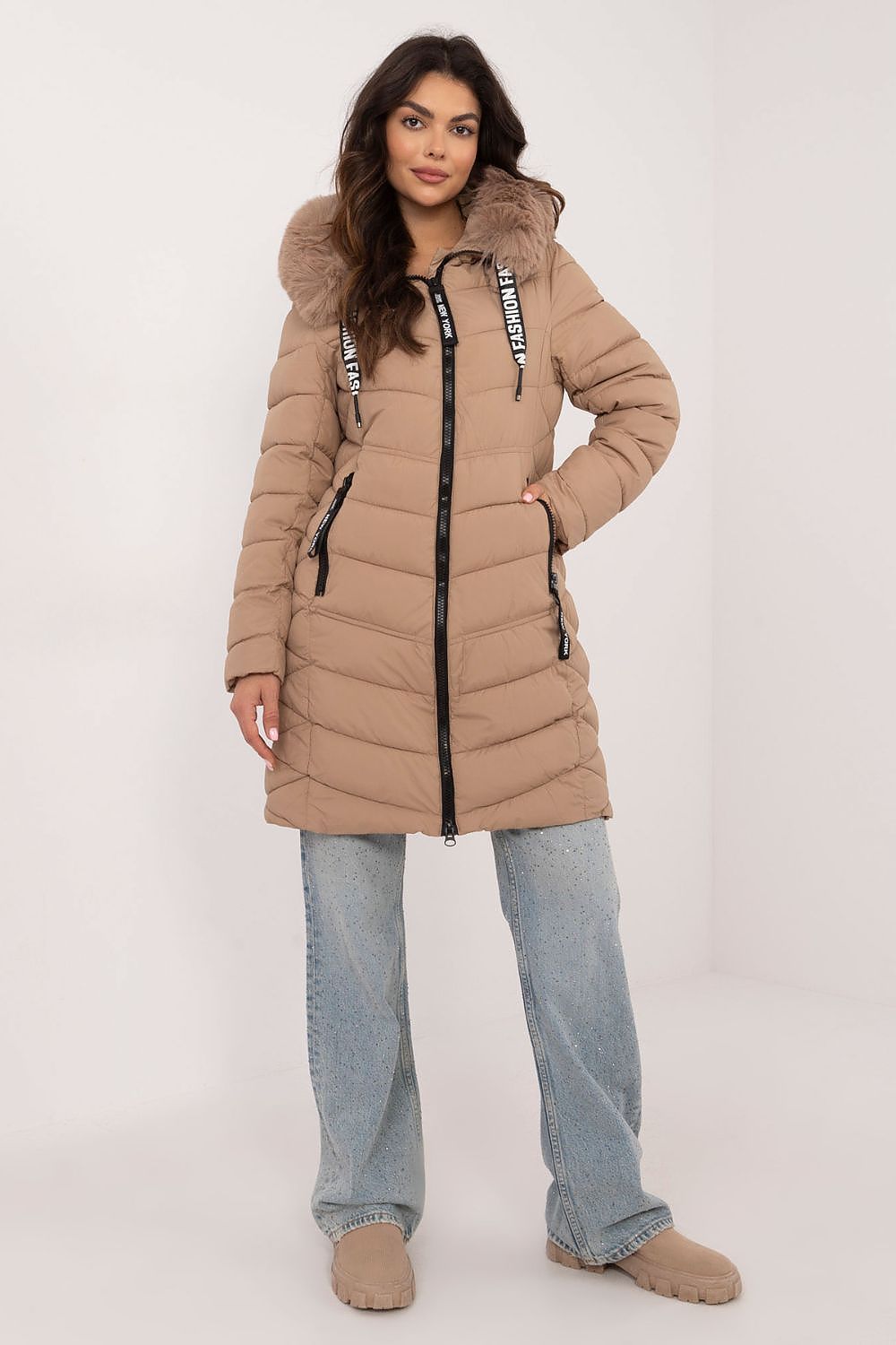 Woman wearing a beige puffer coat with fur hood on a white background