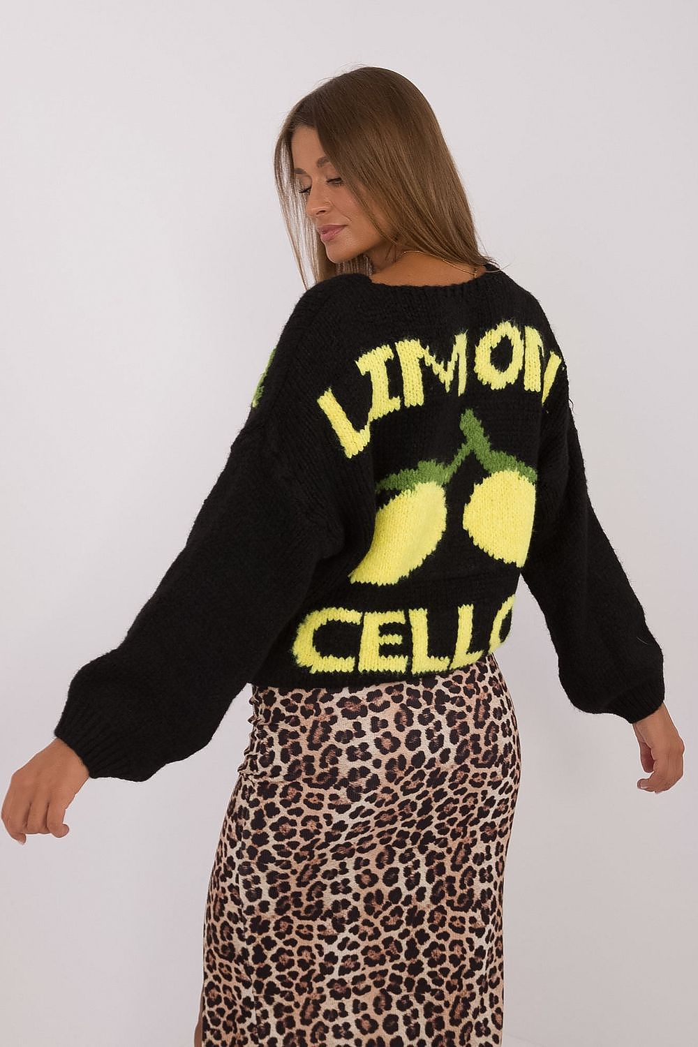 Person wearing a black sweater with 'Limoncello' text and lemon graphics, paired with a leopard print skirt.