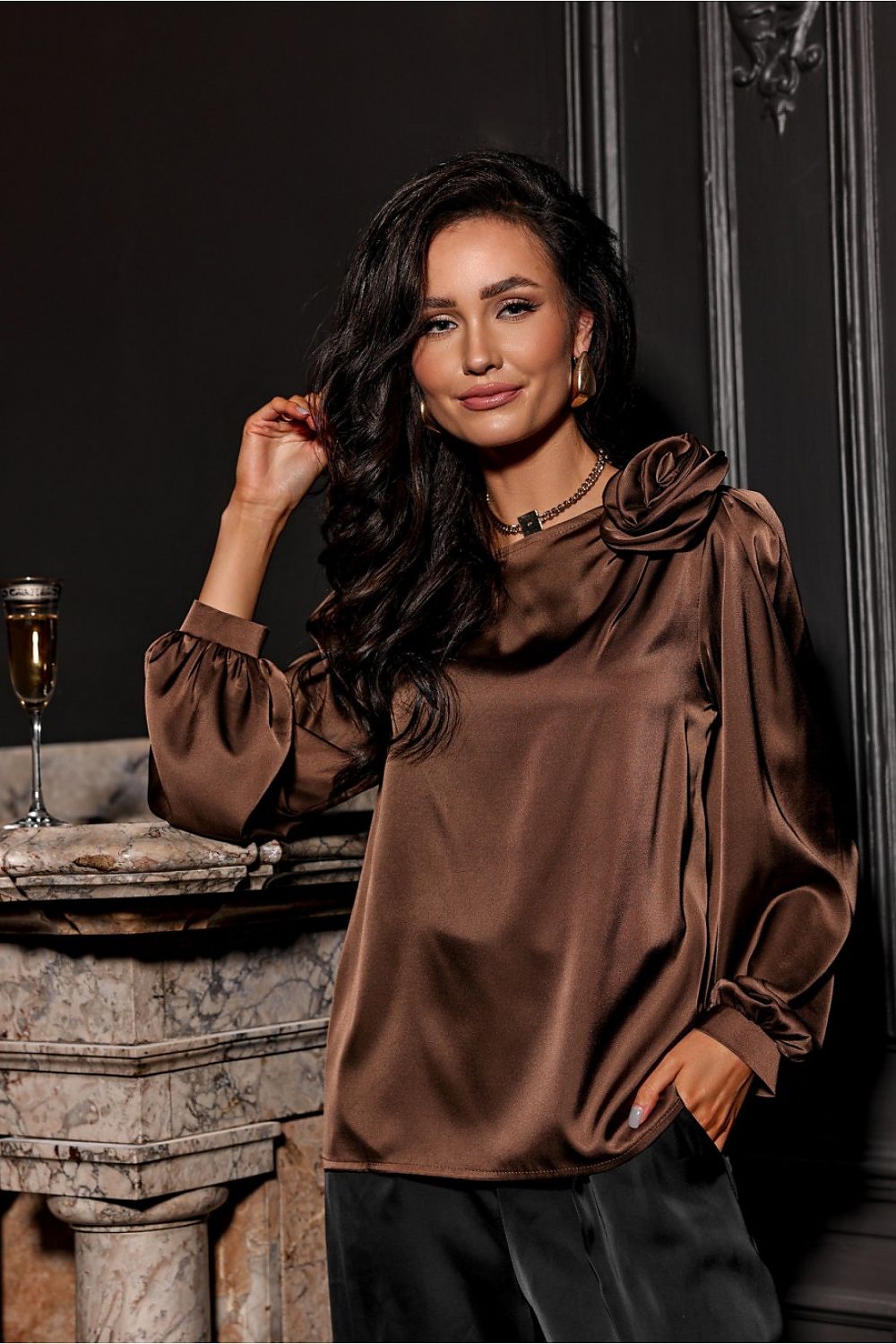 Woman wearing a brown satin blouse in an elegant setting.