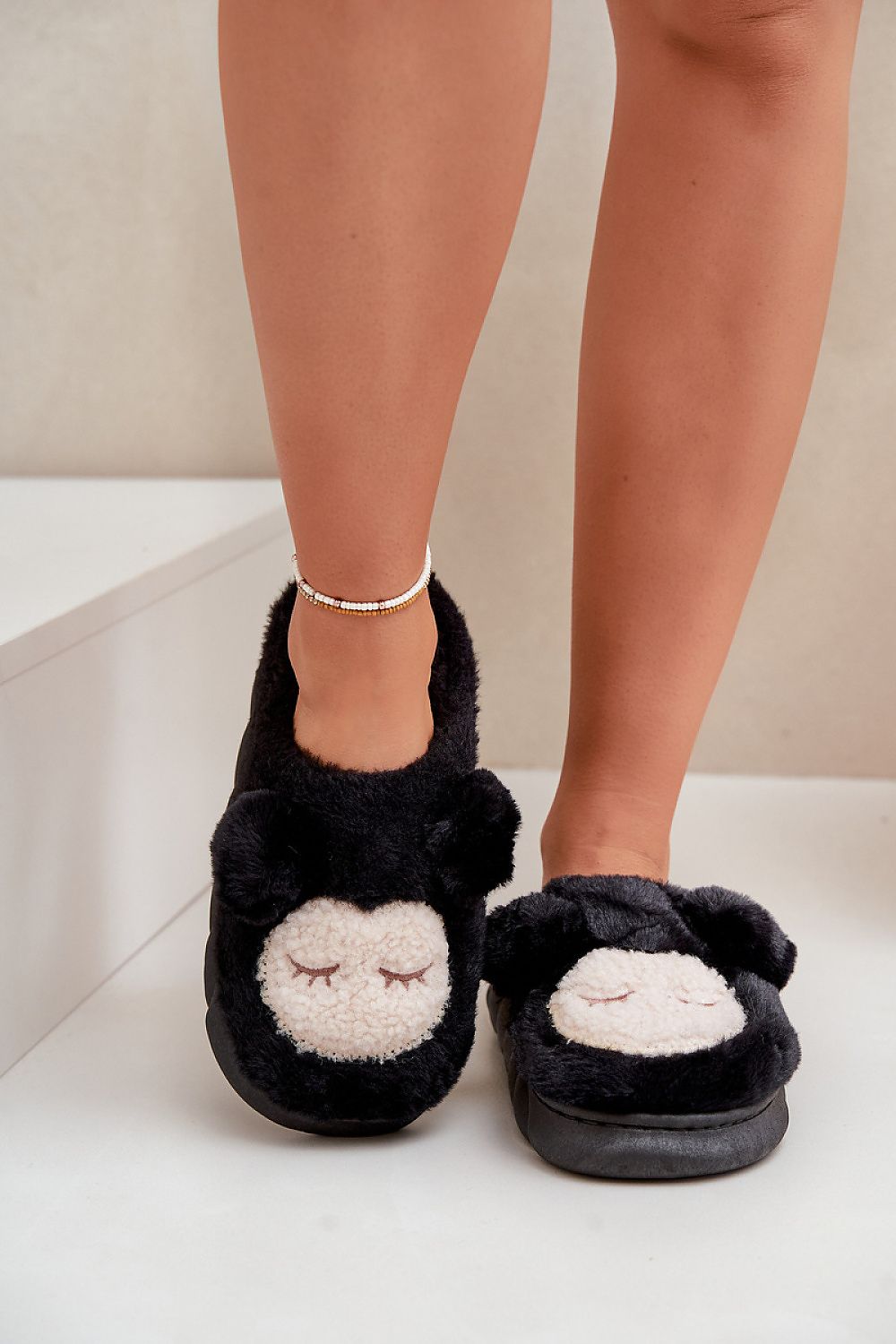 Black slippers with white paw prints worn by a person on a light background