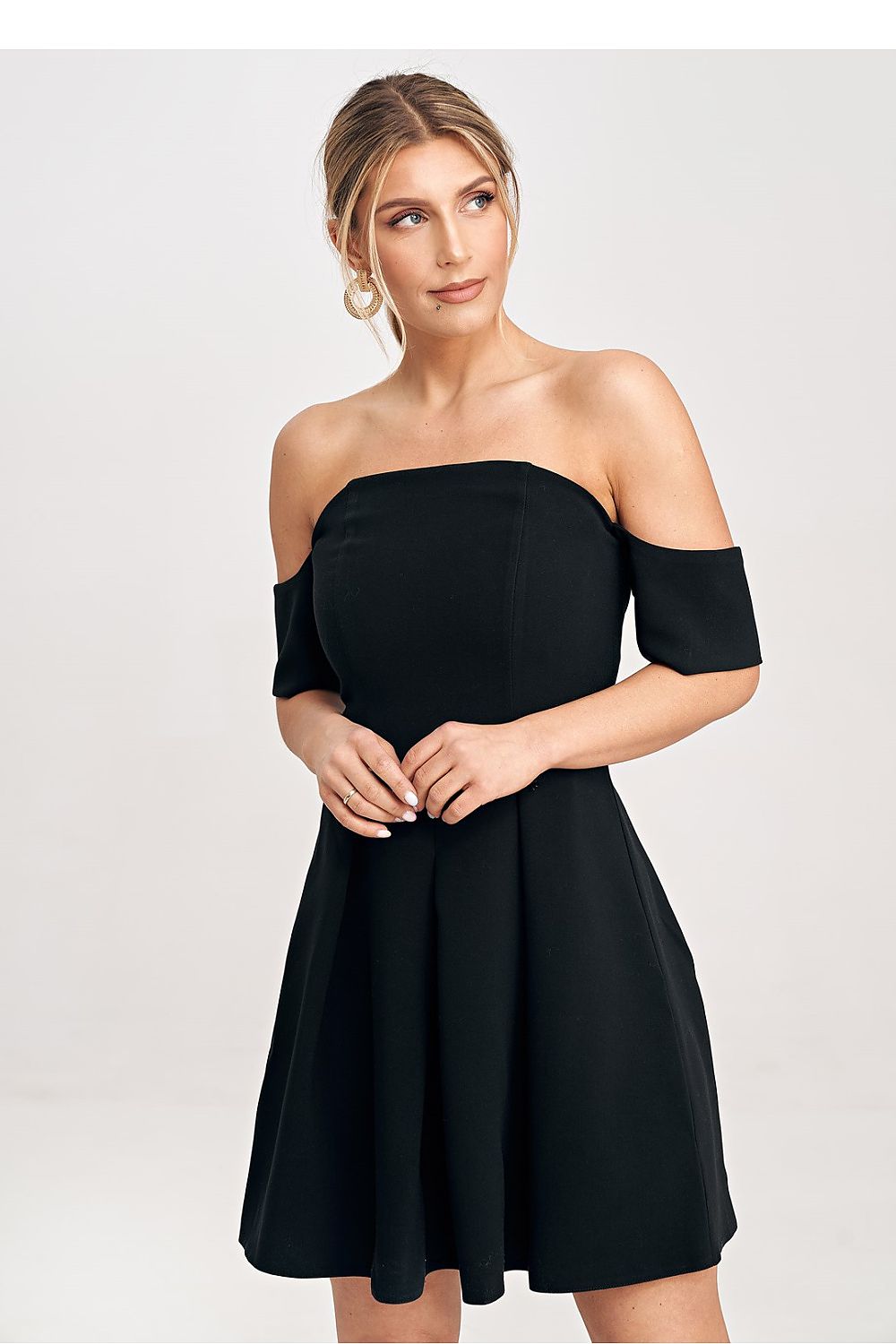 Woman wearing a black off-shoulder dress against a white background
