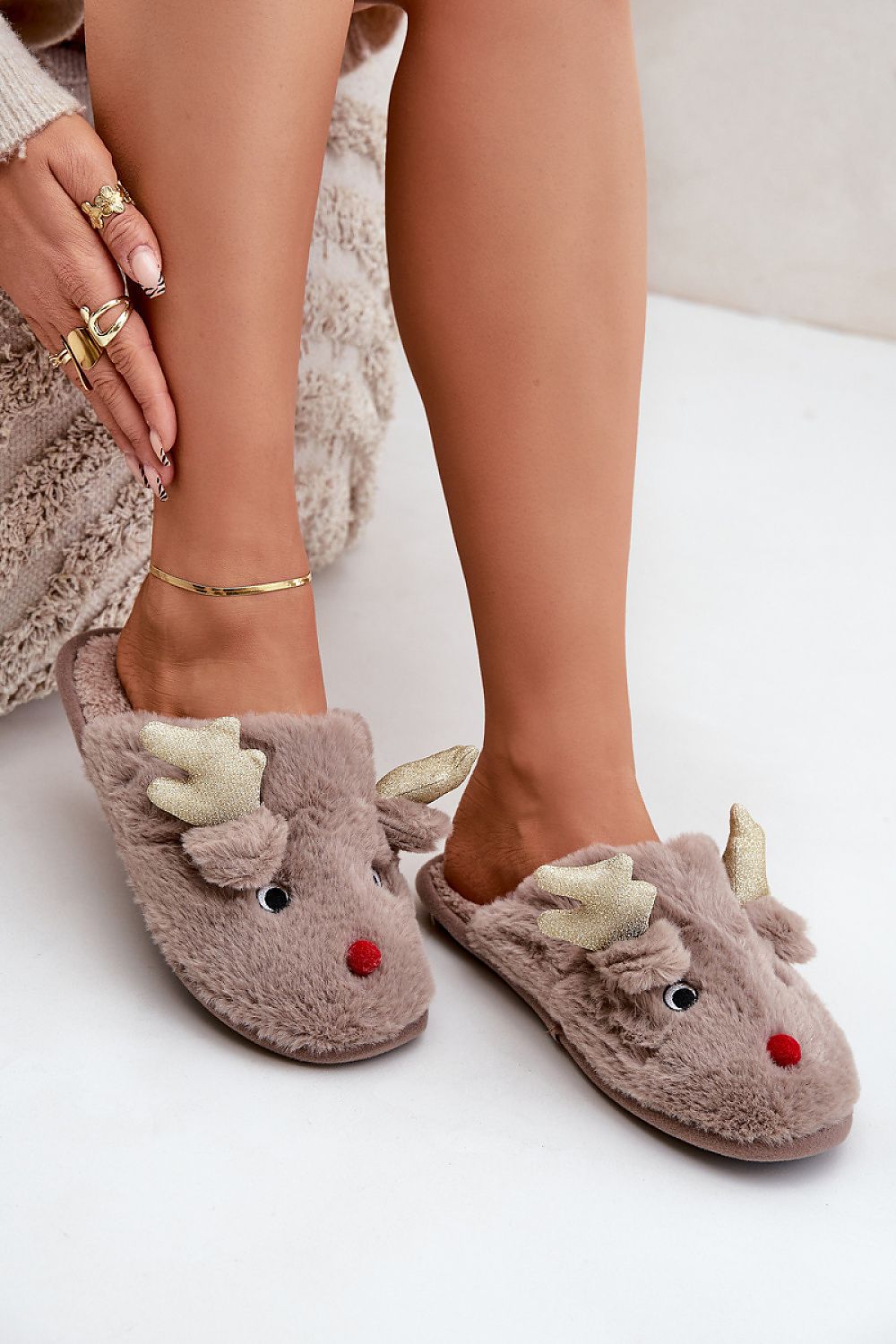 Brown slippers with reindeer design worn by a person on a light background