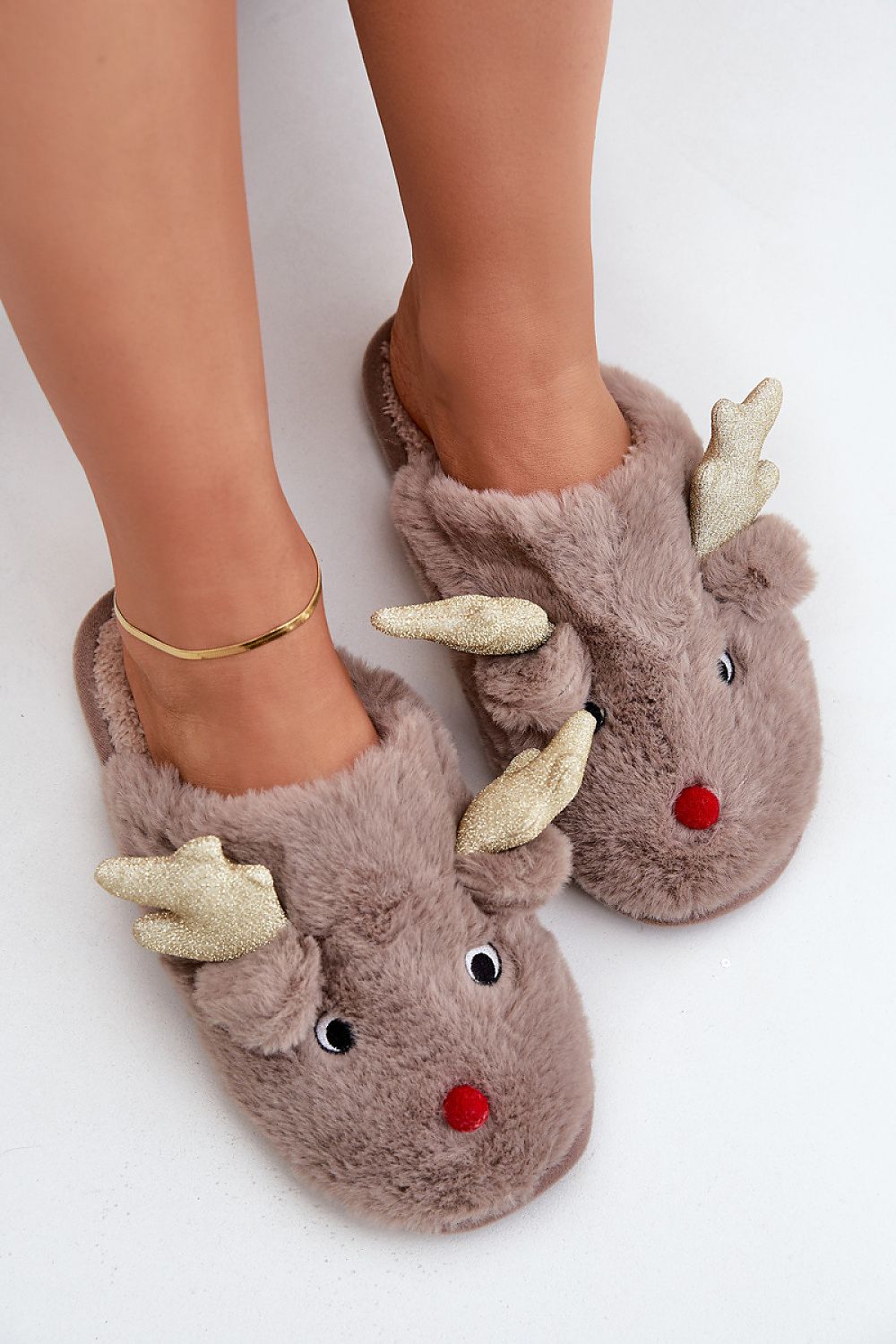 Brown fuzzy slippers shaped like reindeer with antlers and a red nose on a white background.
