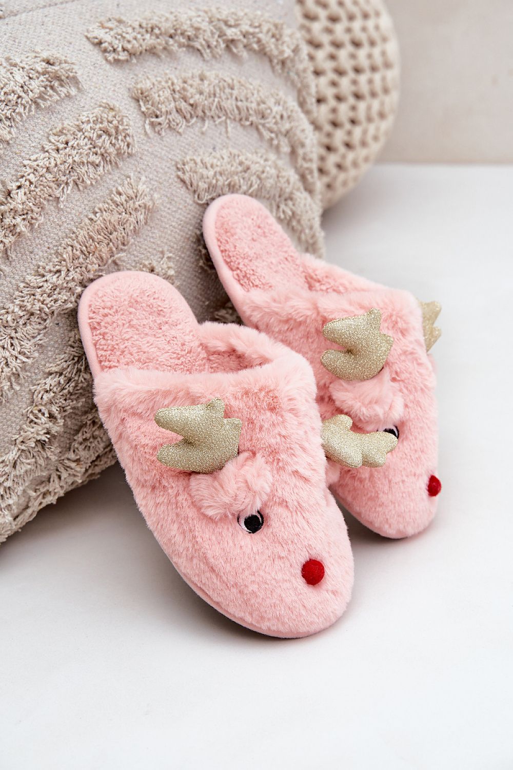 Pink slippers with reindeer design on a white surface