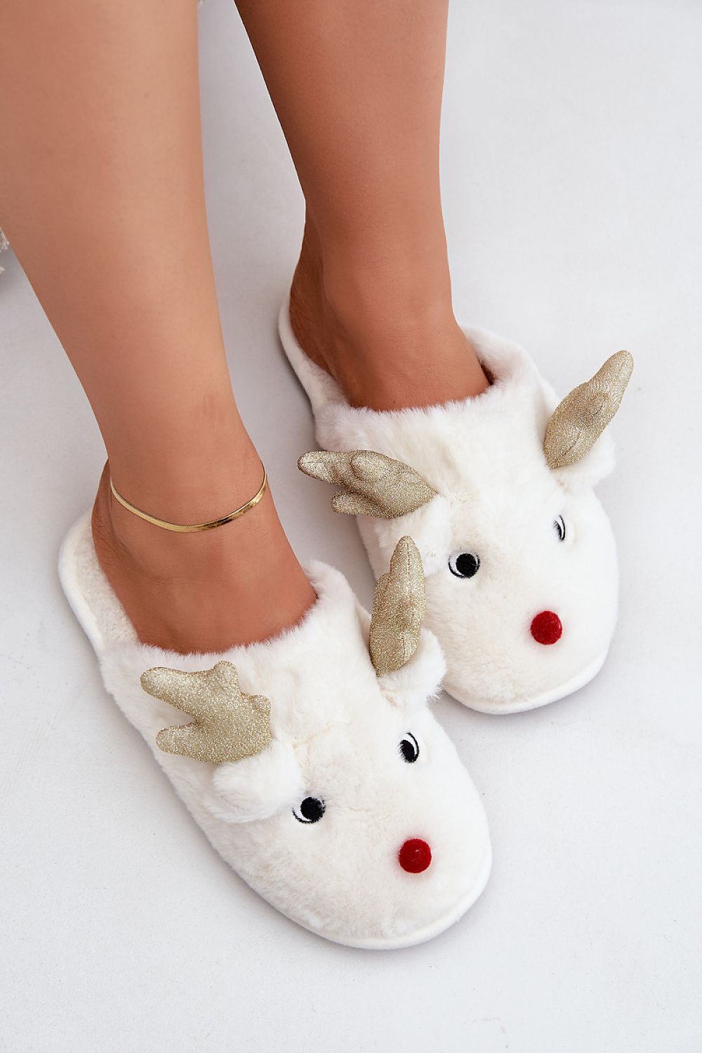 White slippers with reindeer design worn by a person on a light background