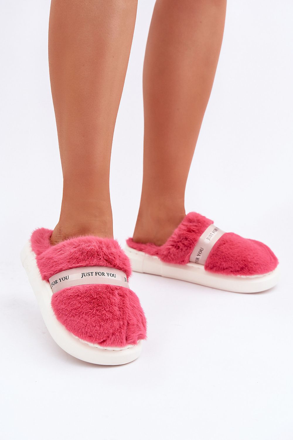Pink fuzzy slippers with white soles on a light background