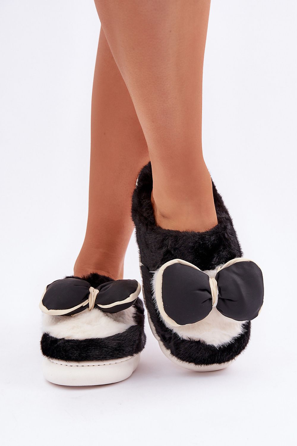 Black and white slippers with bow details on a white background