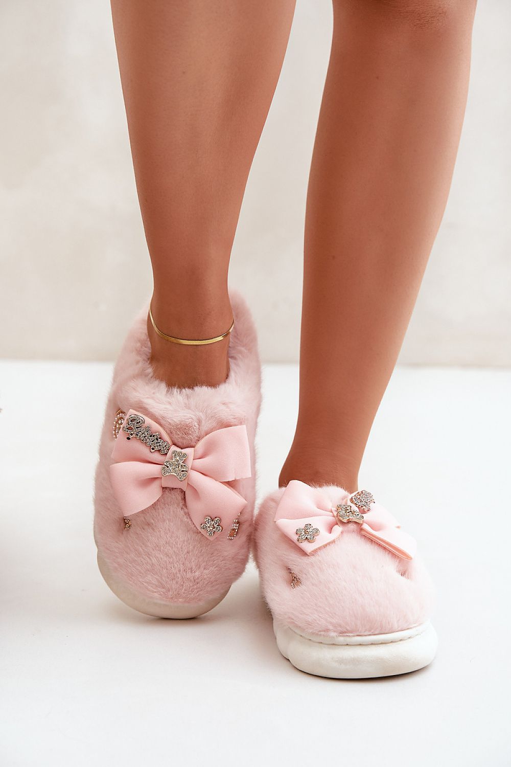Pink slippers with decorative bows and crystals on a light background
