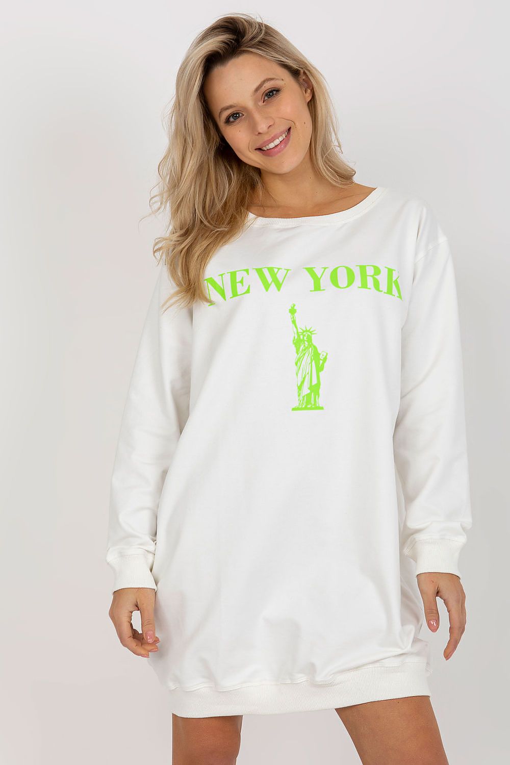 Woman wearing a white sweatshirt with 'New York' and Statue of Liberty graphic on a plain background