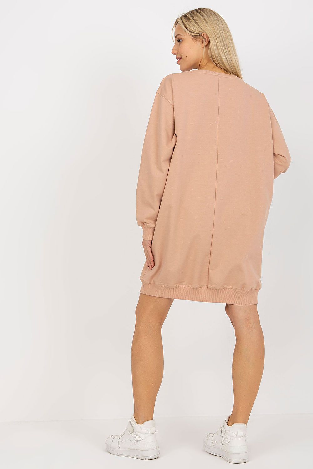 Woman wearing a beige sweatshirt dress on a white background