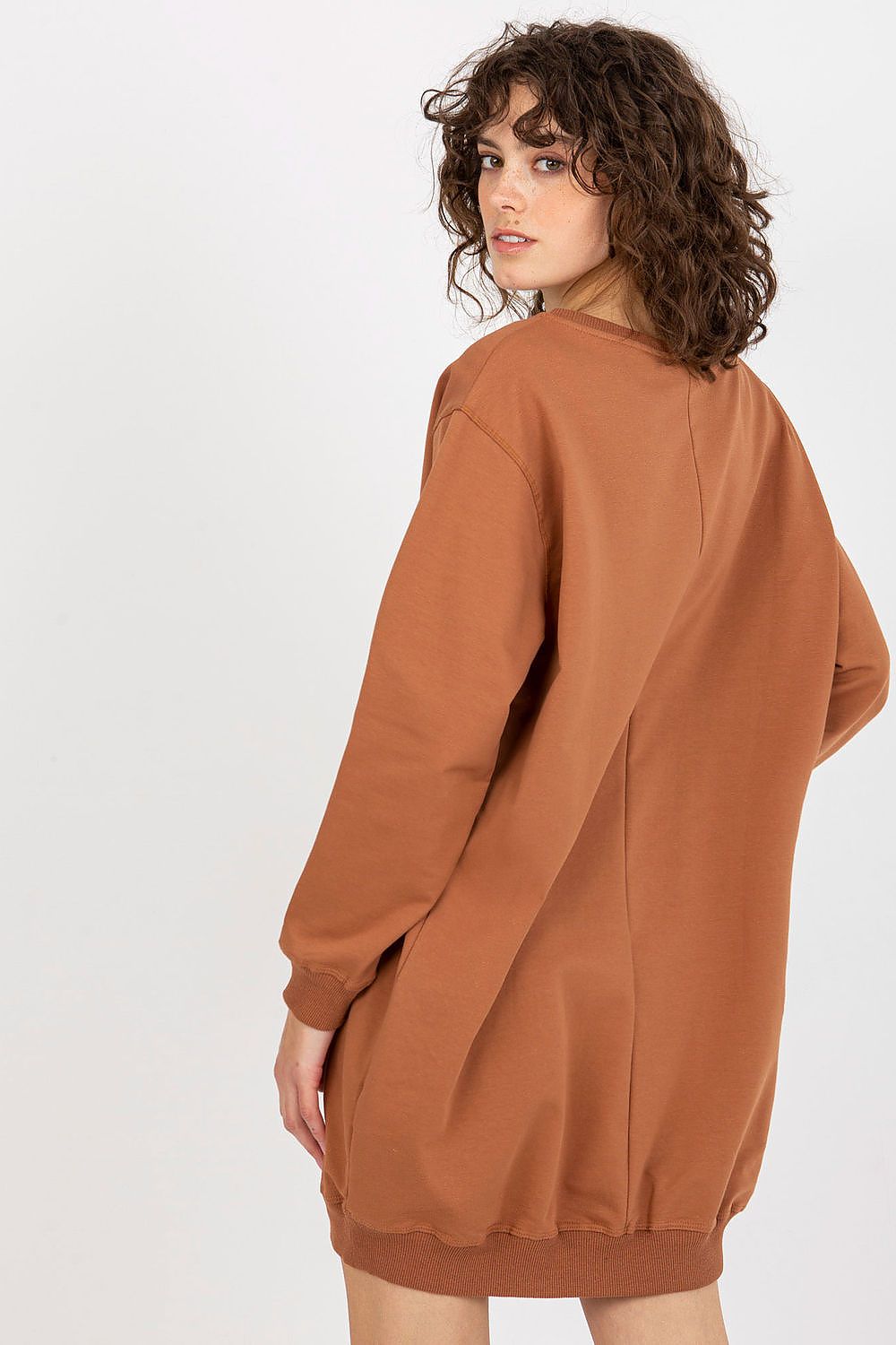 Person wearing a brown sweatshirt dress on a white background