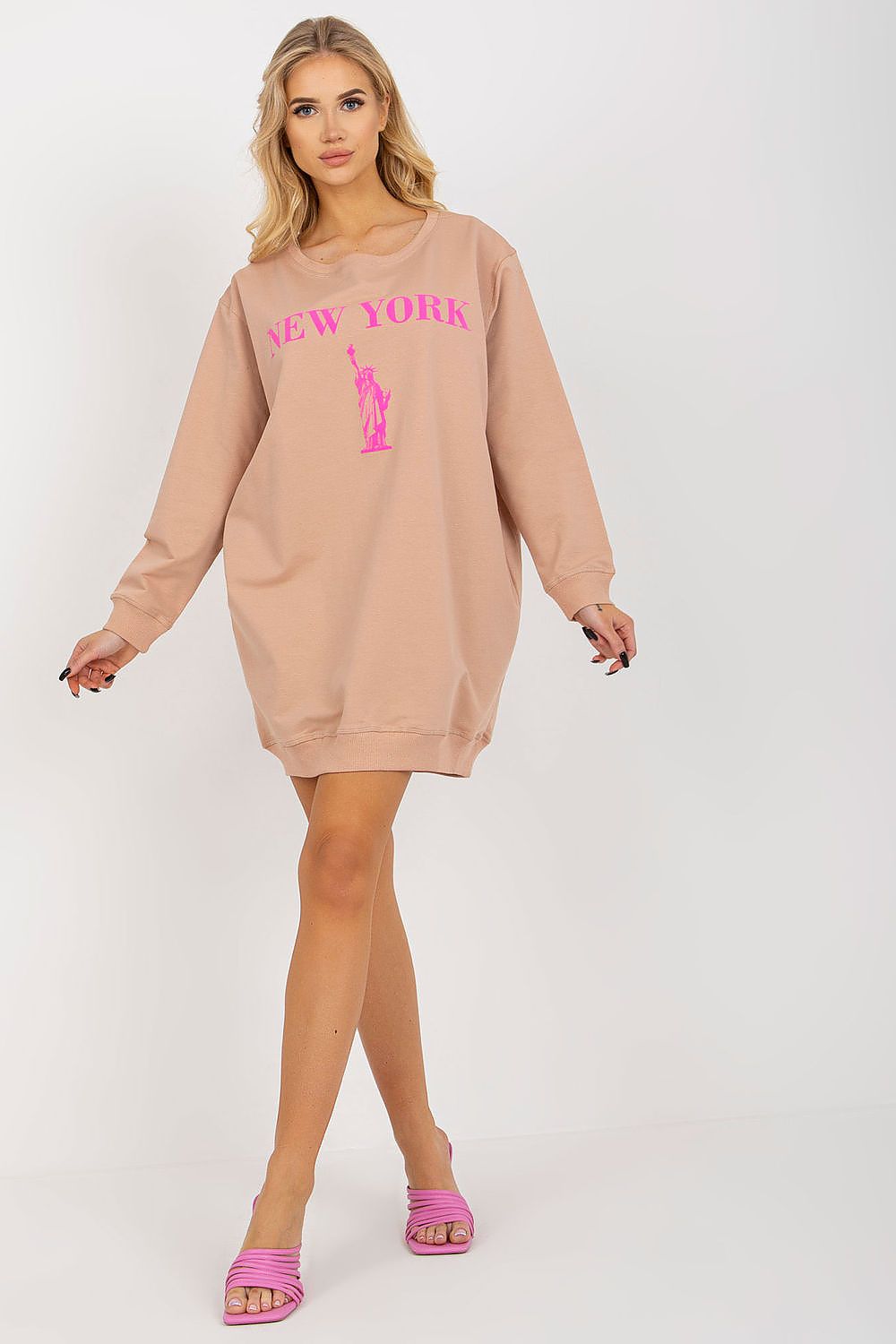 Woman wearing a beige sweatshirt dress with 'New York' print on a white background